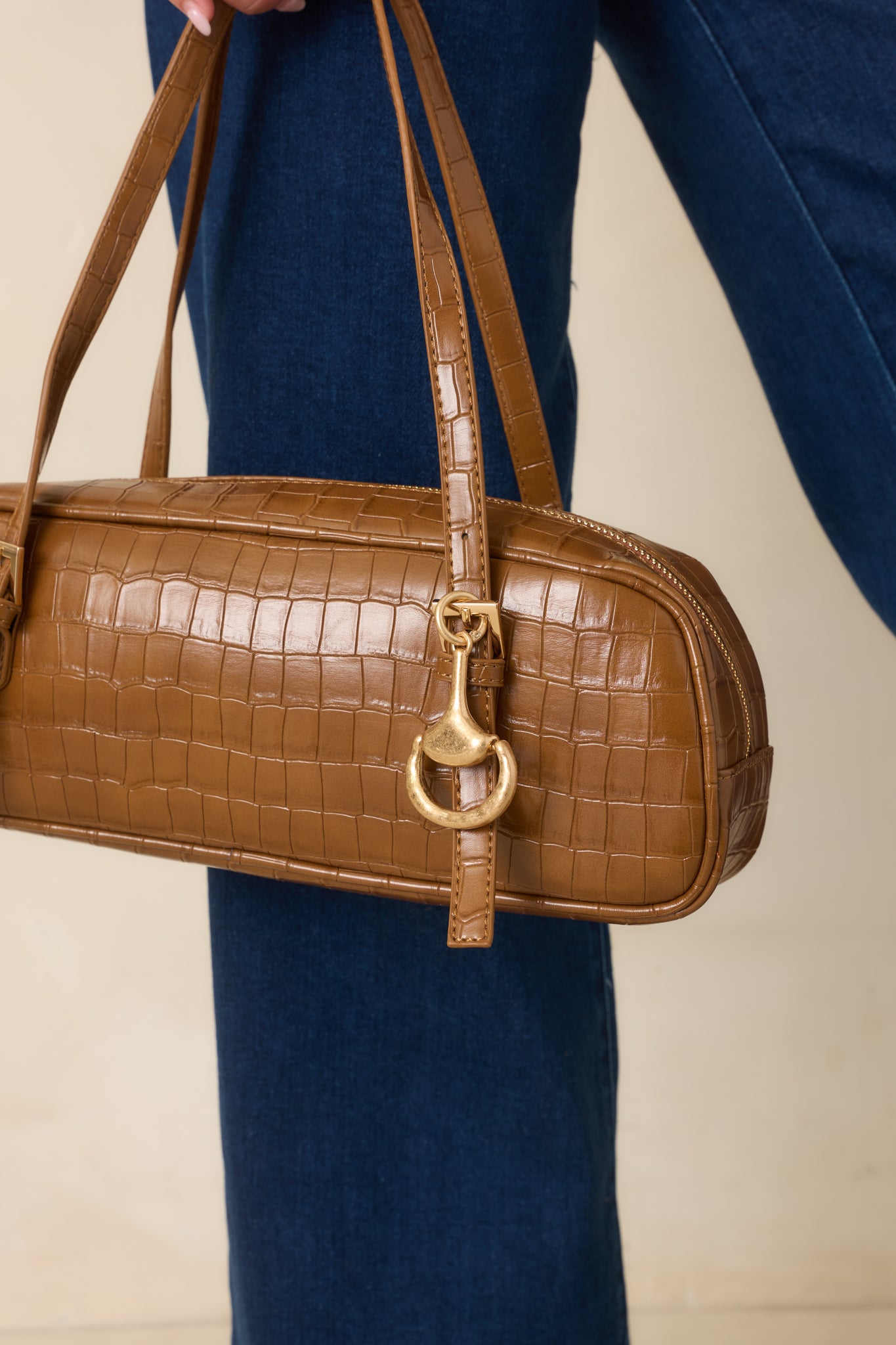 Gold-tone horsebit bag charm featuring a sculptural silhouette, softly textured finish, and spring-ring clasp for an elevated hardware-inspired accent.