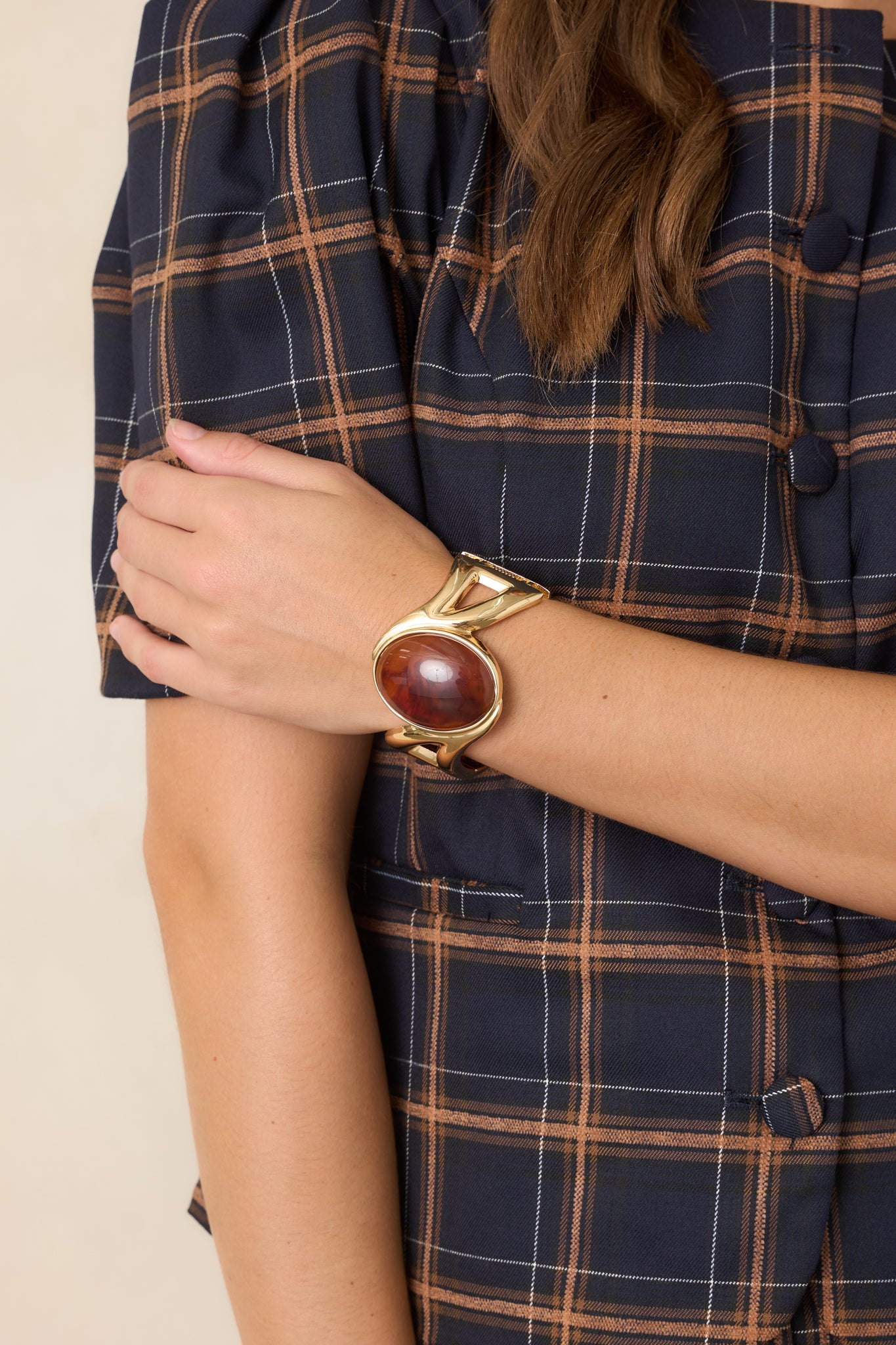 Open gold-tone bracelet showcasing its bold geometric design and rich amber accent at the center.