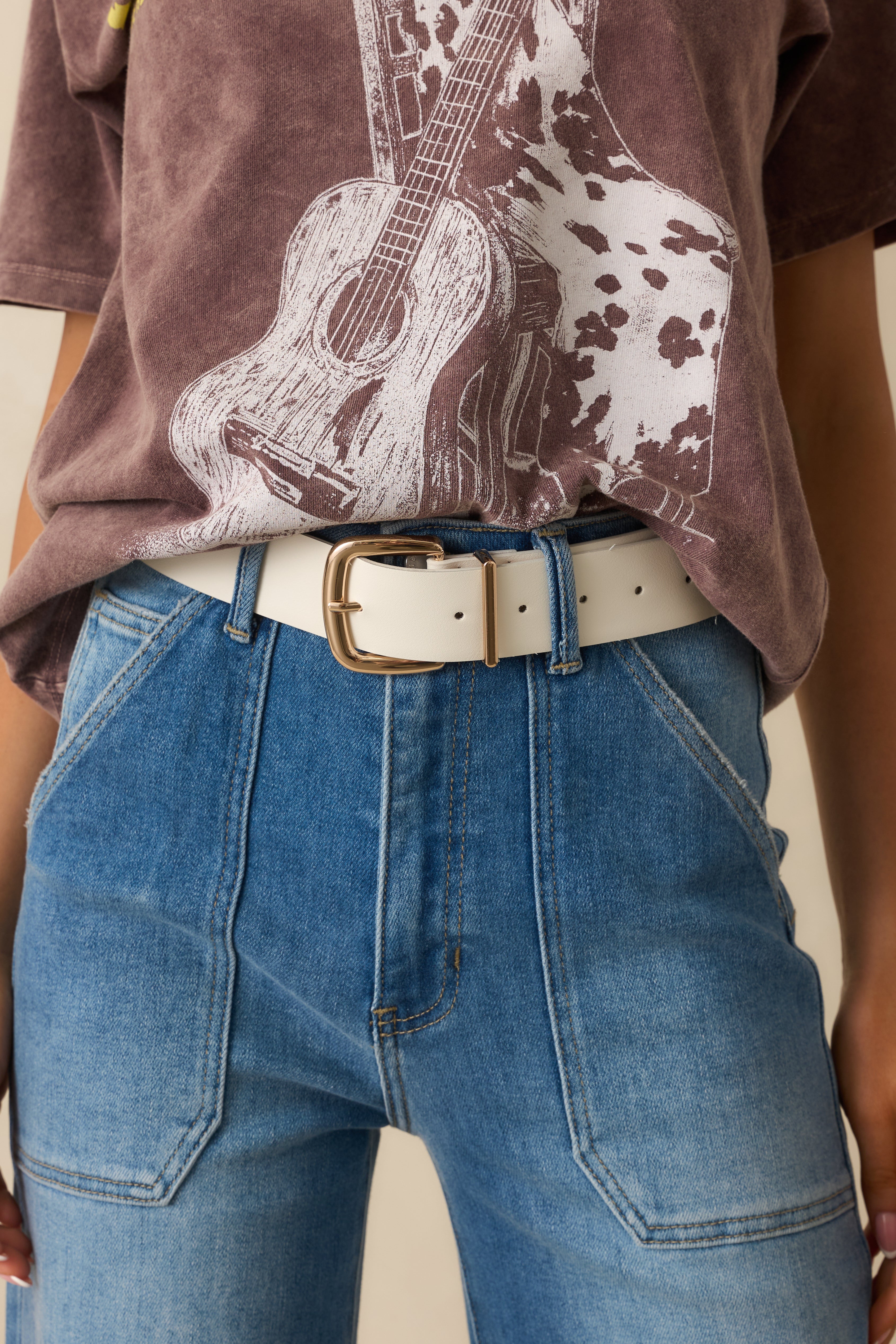 Close-up of the gold-tone square buckle, stitched edges, and smooth faux leather texture.