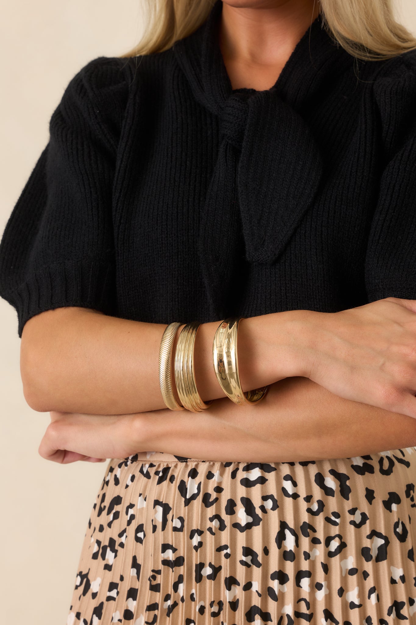 Trio of gold-tone bangles featuring polished, textured, and ridged finishes for a layered statement jewelry look.