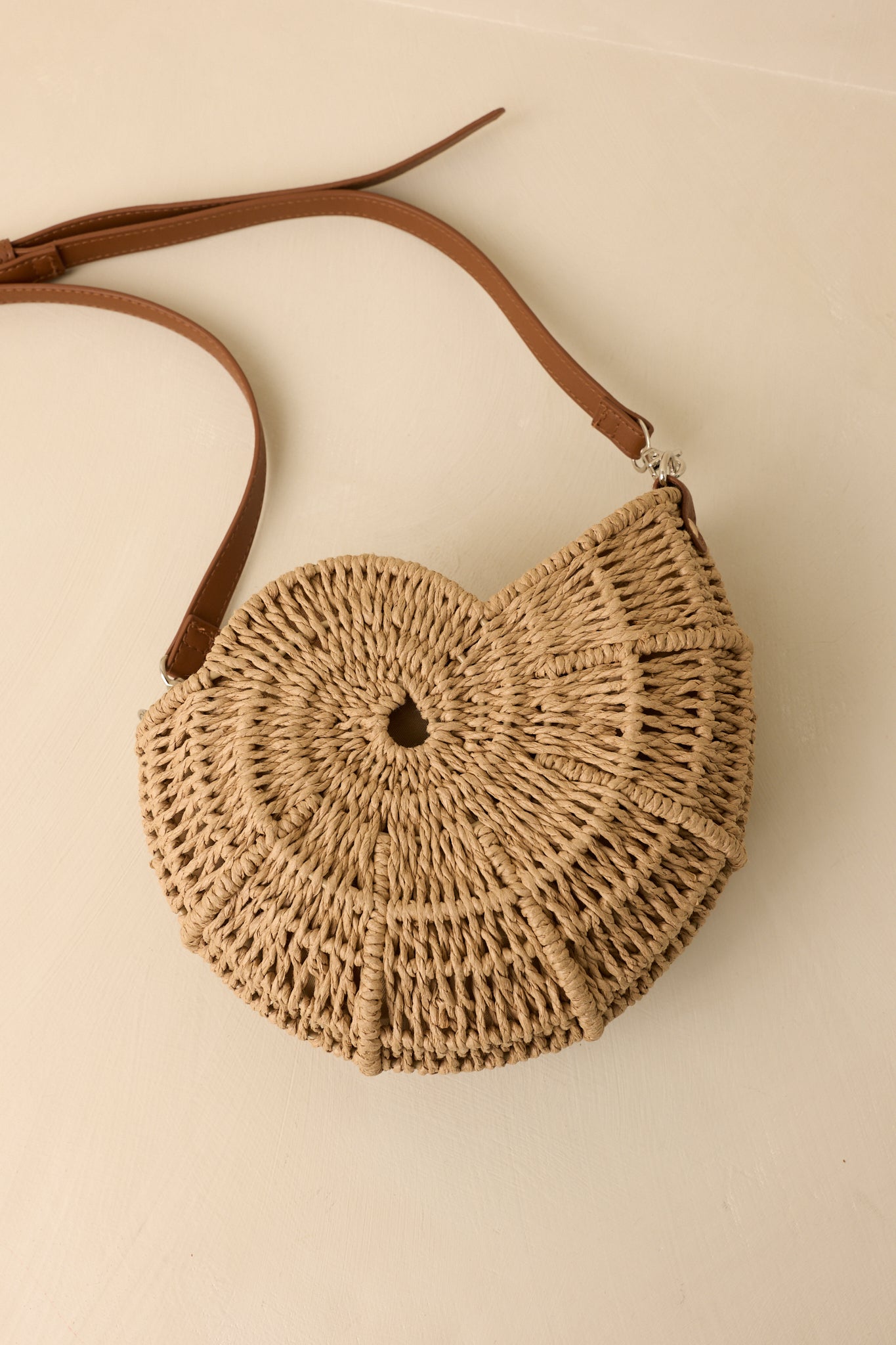 Golden woven crossbody bag featuring a structured nautilus-inspired silhouette, spiral detailing, faux leather strap, and metal hardware.