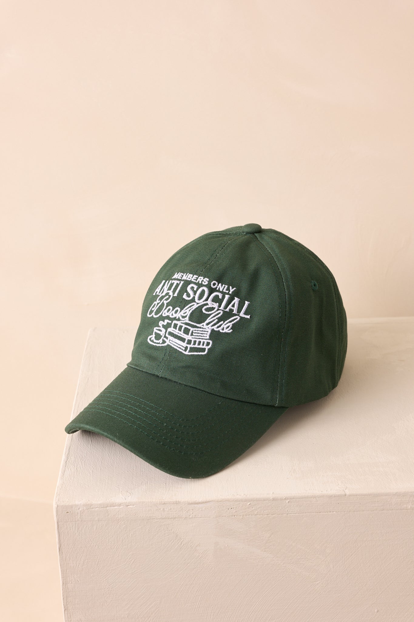 A slightly overhead view of the green baseball cap emphasizing the stitched eyelets and crown shape.