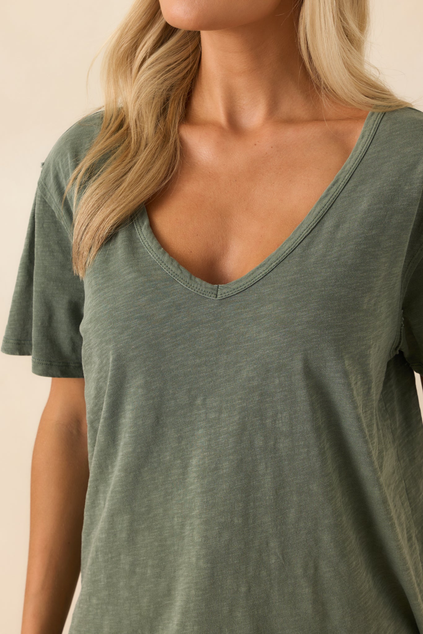 A close-up detail of the v-neckline and subtle texture of the hunter green cotton.