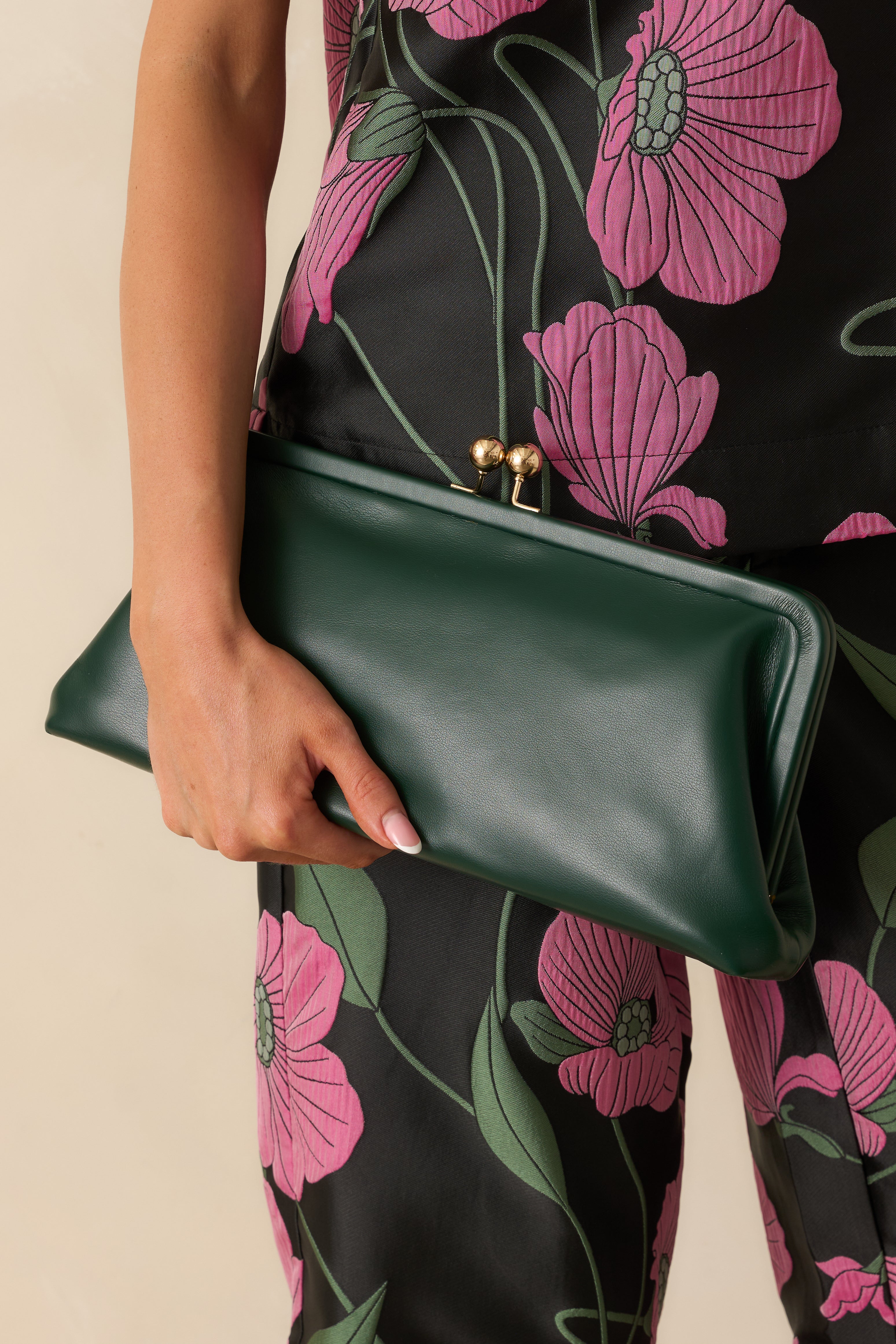 Front view of green faux leather clutch handbag featuring a structured frame silhouette and gold-tone kiss-lock closure.