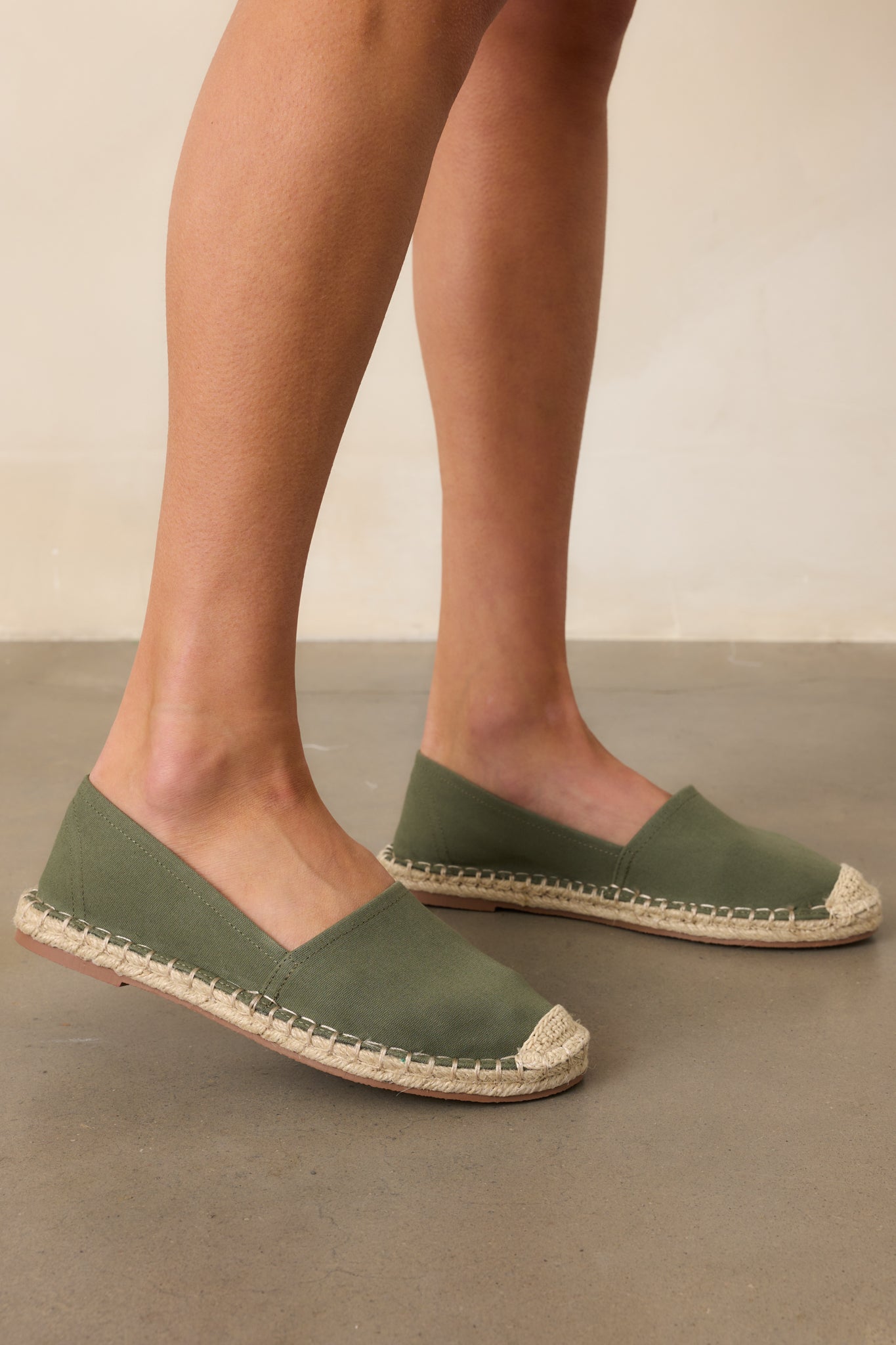 A side profile of the green flats, showcasing the jute-wrapped espadrille sole and low-cut opening.