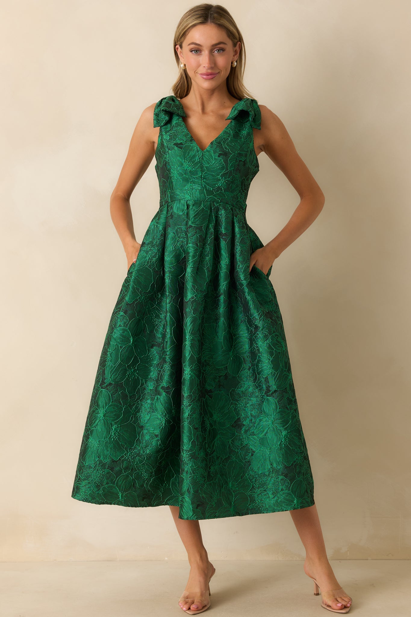 Green floral midi dress with self-tie bow straps, v-neckline, sleeveless design, and side pockets.