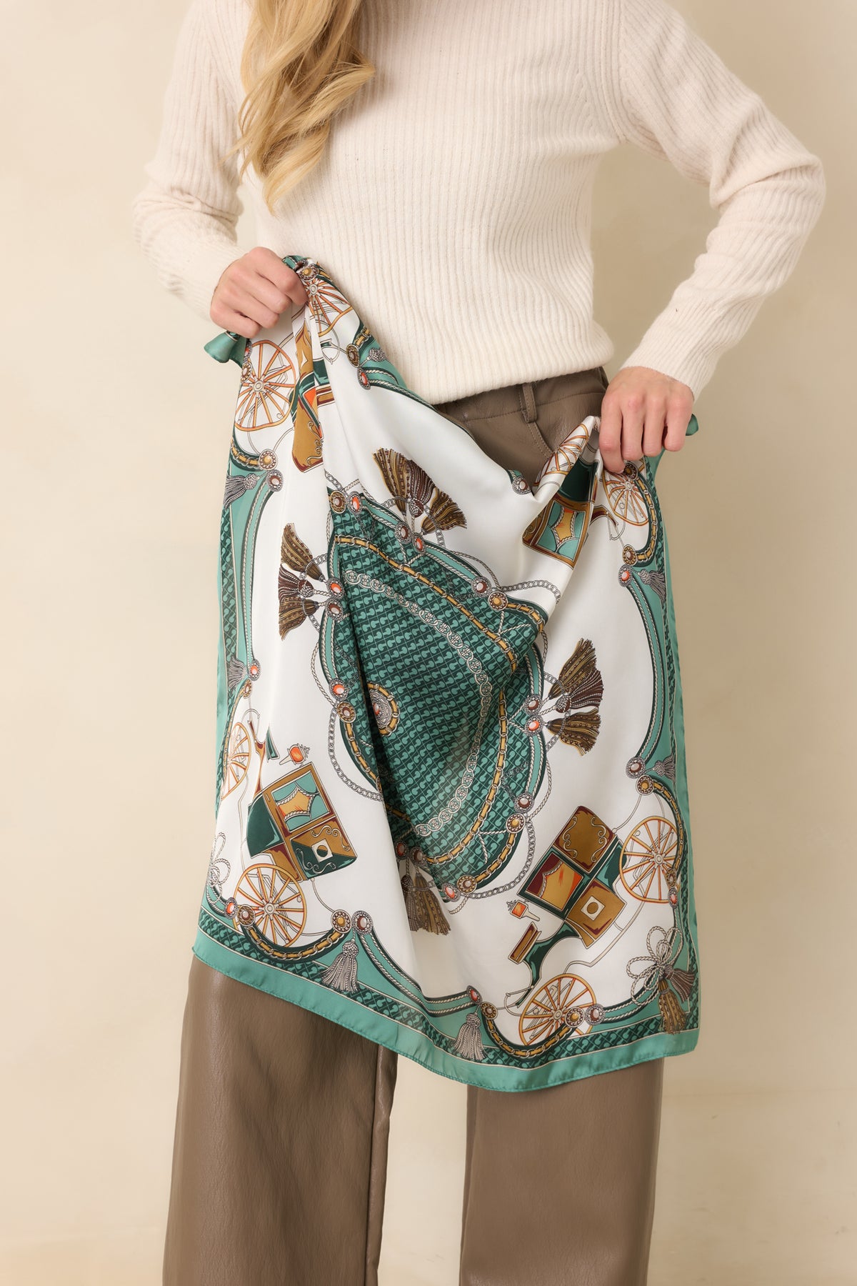 Silky square scarf showcasing an intricate green and ivory pattern with golden carriage wheels, decorative medallions, interwoven chains, and a contrasting green border.