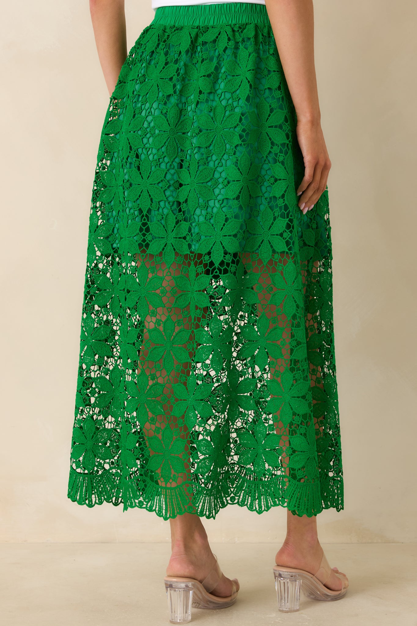 Green lace maxi skirt with elastic waistband and flowing rear silhouette.