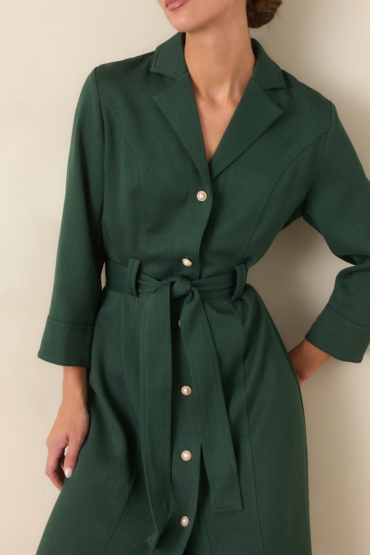 Pearl buttons and gold-tone frames create a polished detail along the green dress front.