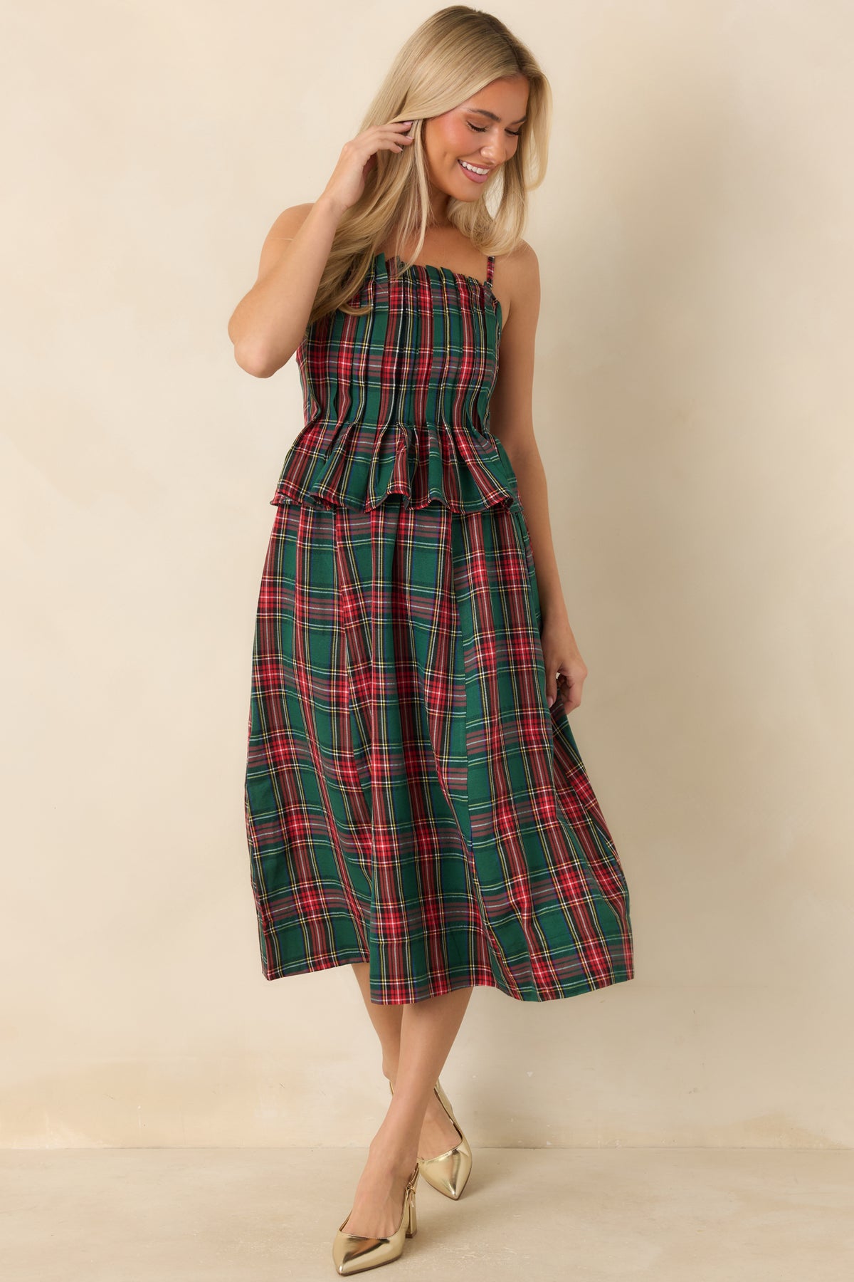 Festive plaid midi dress with a defined peplum waist and a full skirt in a classic green pattern.