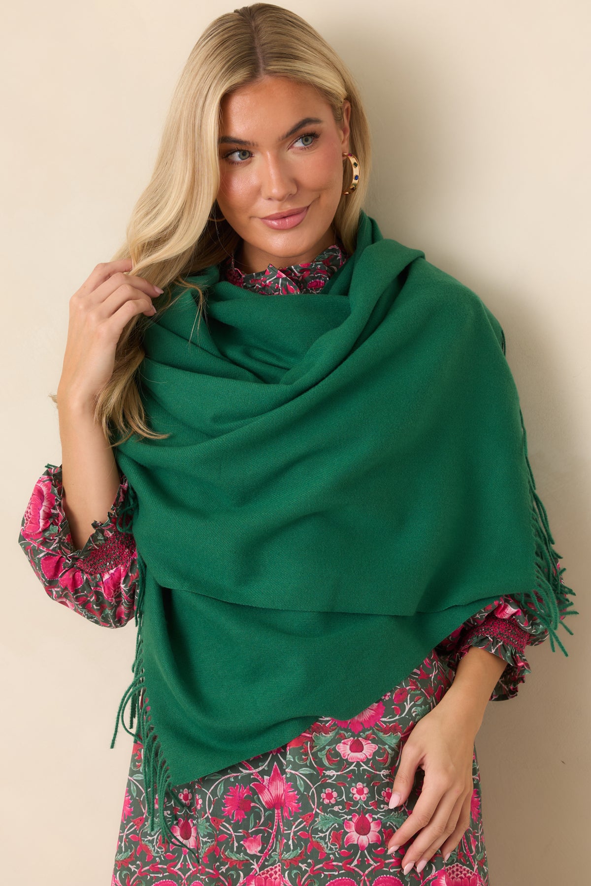 Soft green scarf wrapped in layered folds with fringe detailing along the edge.
