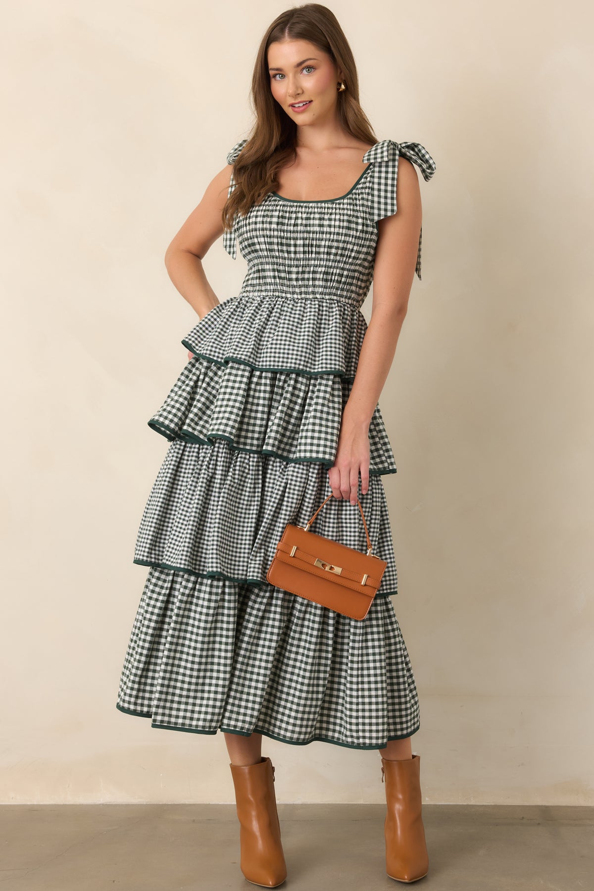 Green midi dress with a softly rounded scoop neckline, elasticized waist, smocked upper bodice, and gently swaying tiered skirt.