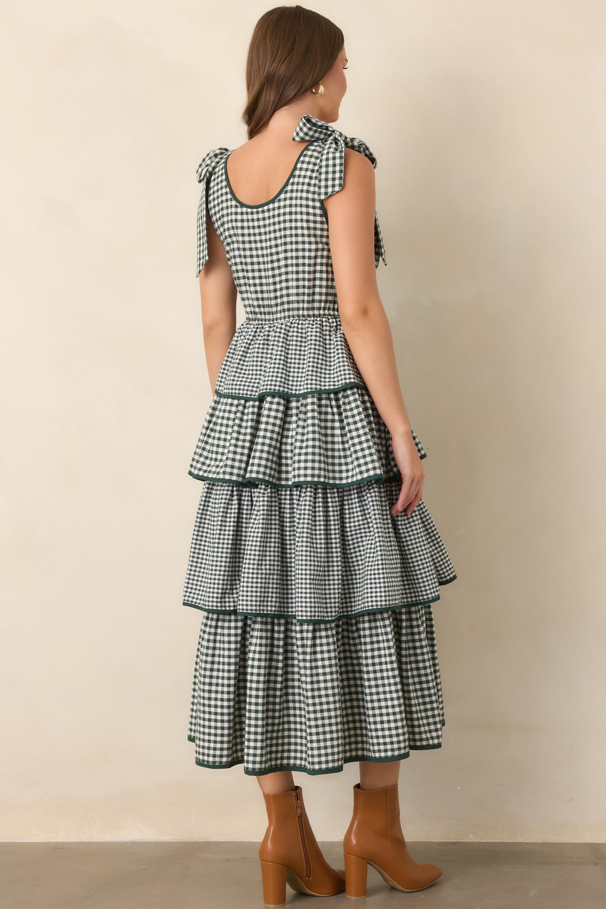 Rear view of the green tiered dress showcasing the smocked bodice, elasticized waist, fixed shoulder ties, and flowing tiers.