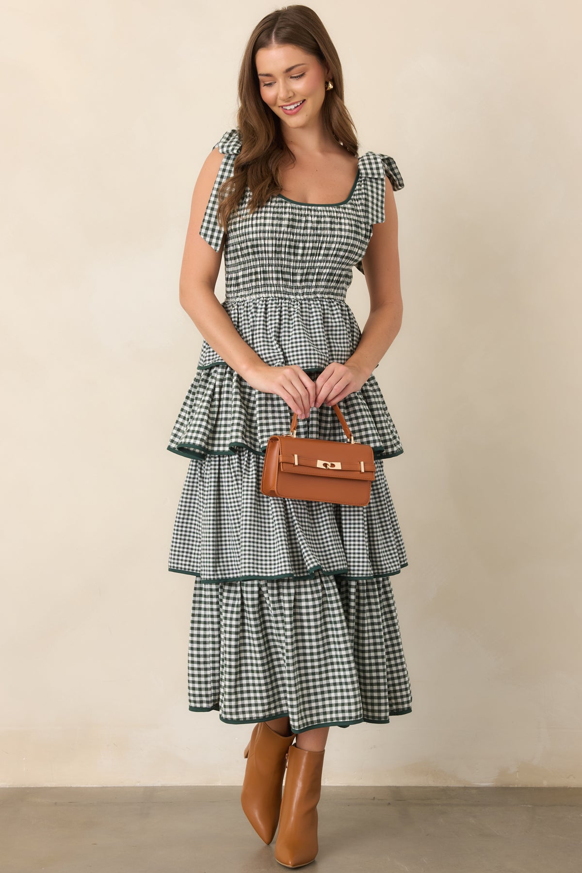 Green tiered dress featuring a smocked bodice, elasticized waist, scoop neckline, fixed shoulder ties, and coordinating green trim.
