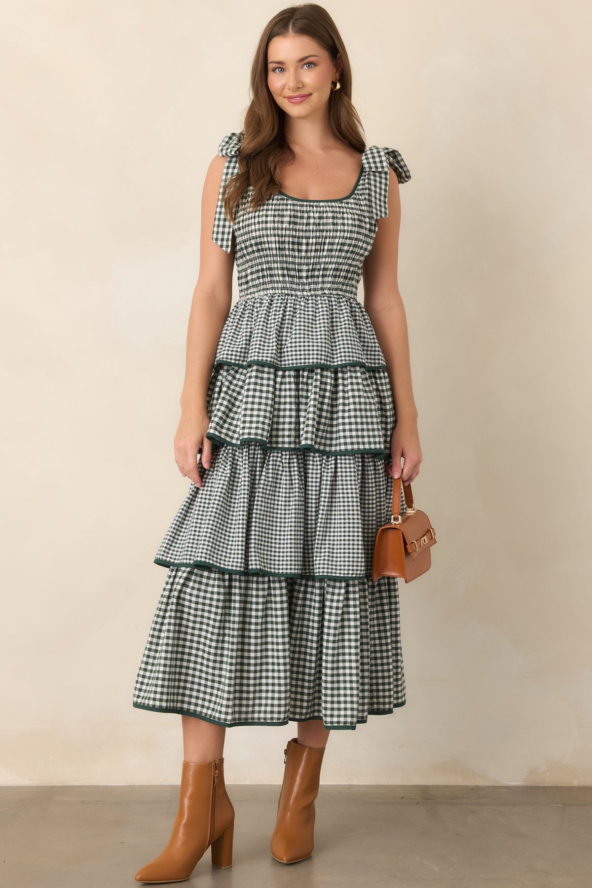Tiered green dress showcasing its comfortable smocked bodice, defined waist, playful shoulder ties, and flowing four-tier silhouette.