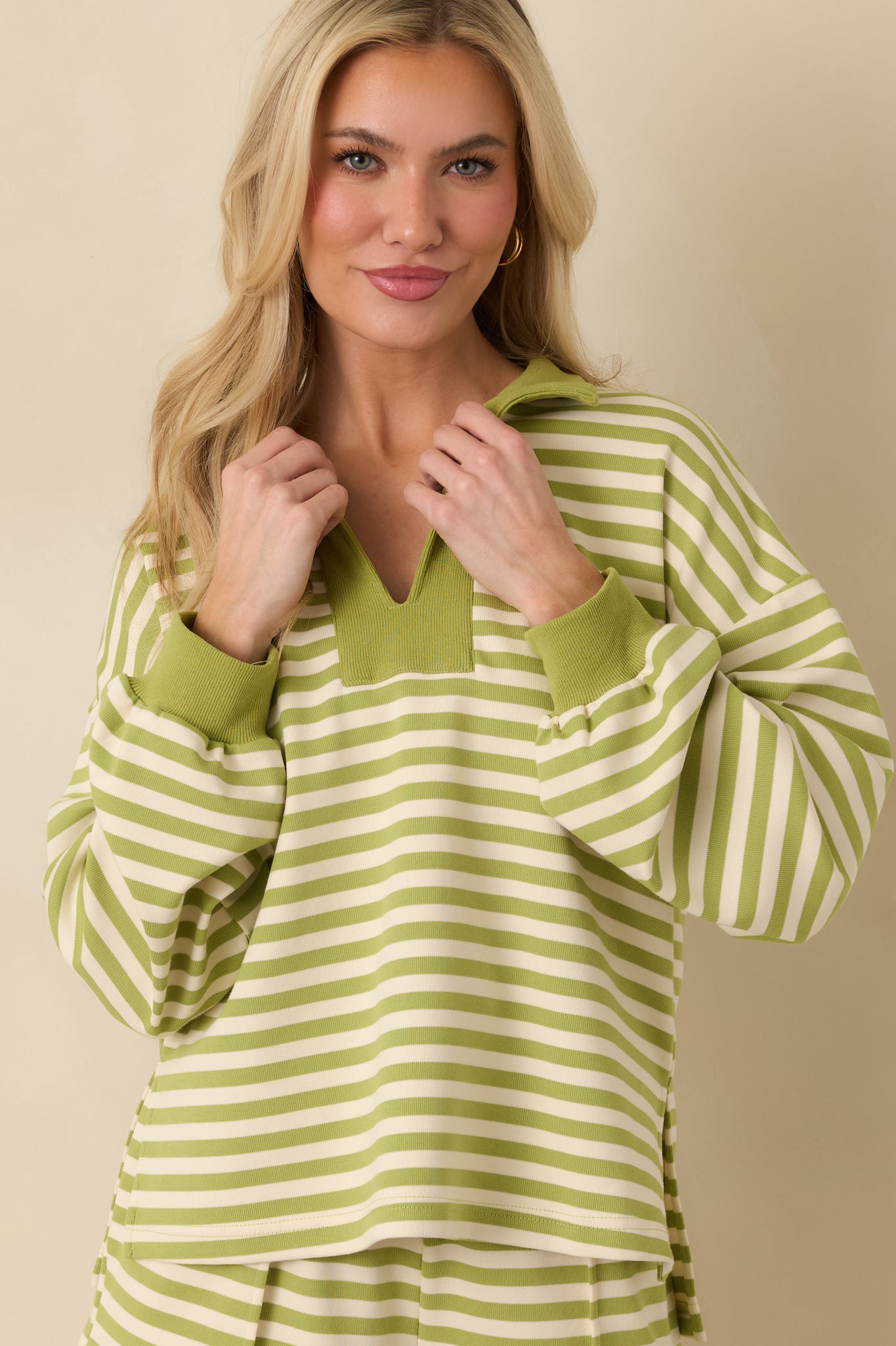 Green striped knit top emphasizing the ribbed hem and smooth knit fabric texture.
