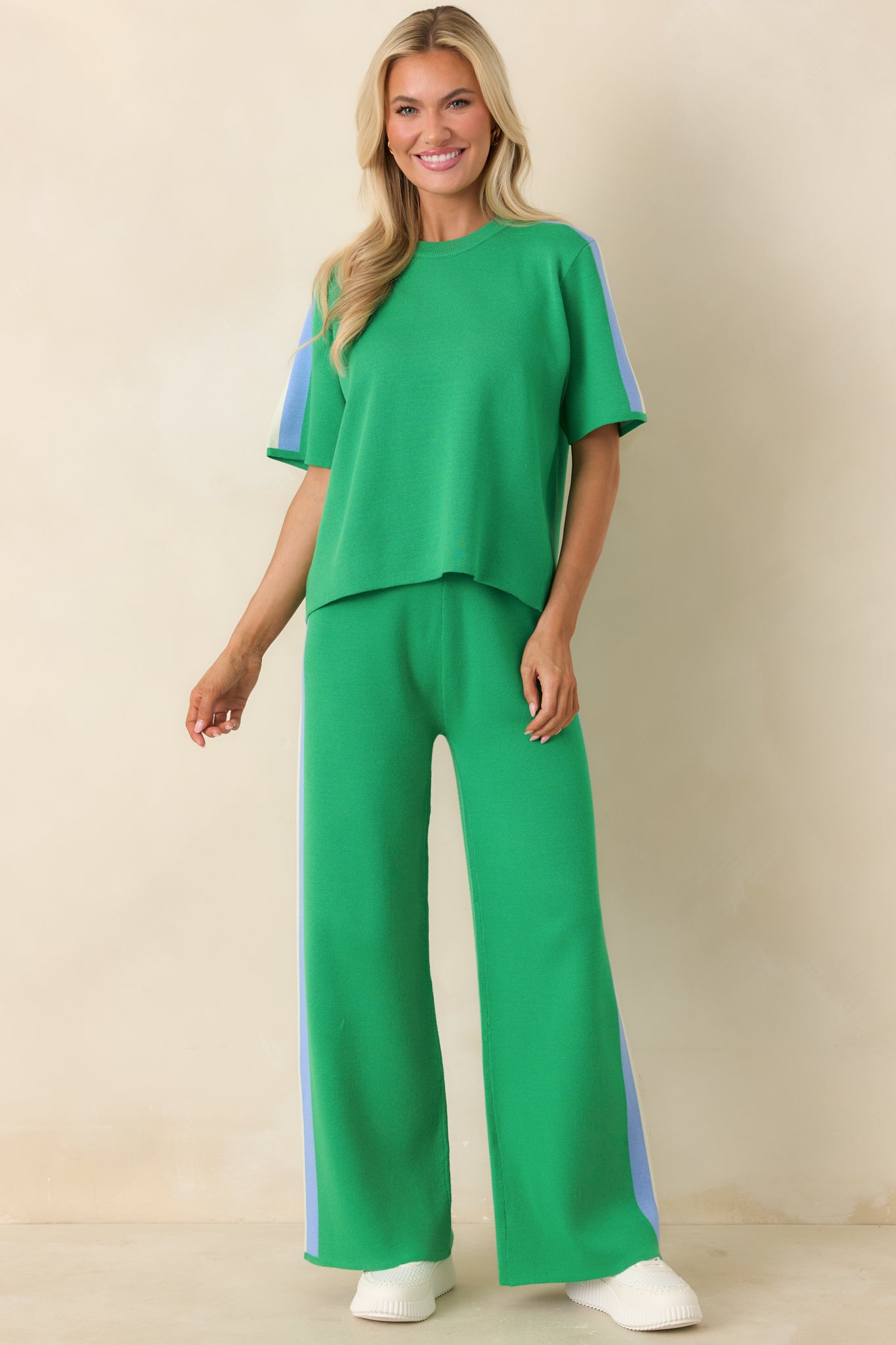 Green knit top with relaxed fit, short sleeves, and multi-colored stripe accents on shoulders.