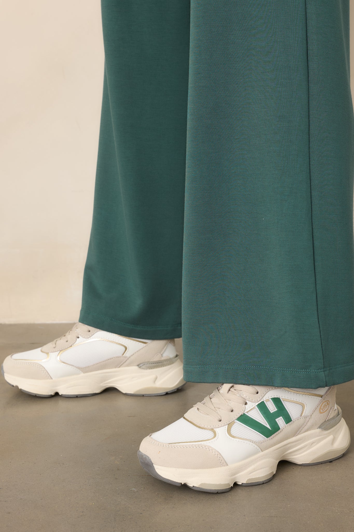 Detailed view of the sneaker uppers featuring green, white, and tan panels with contrasting tan laces and a rounded toe.