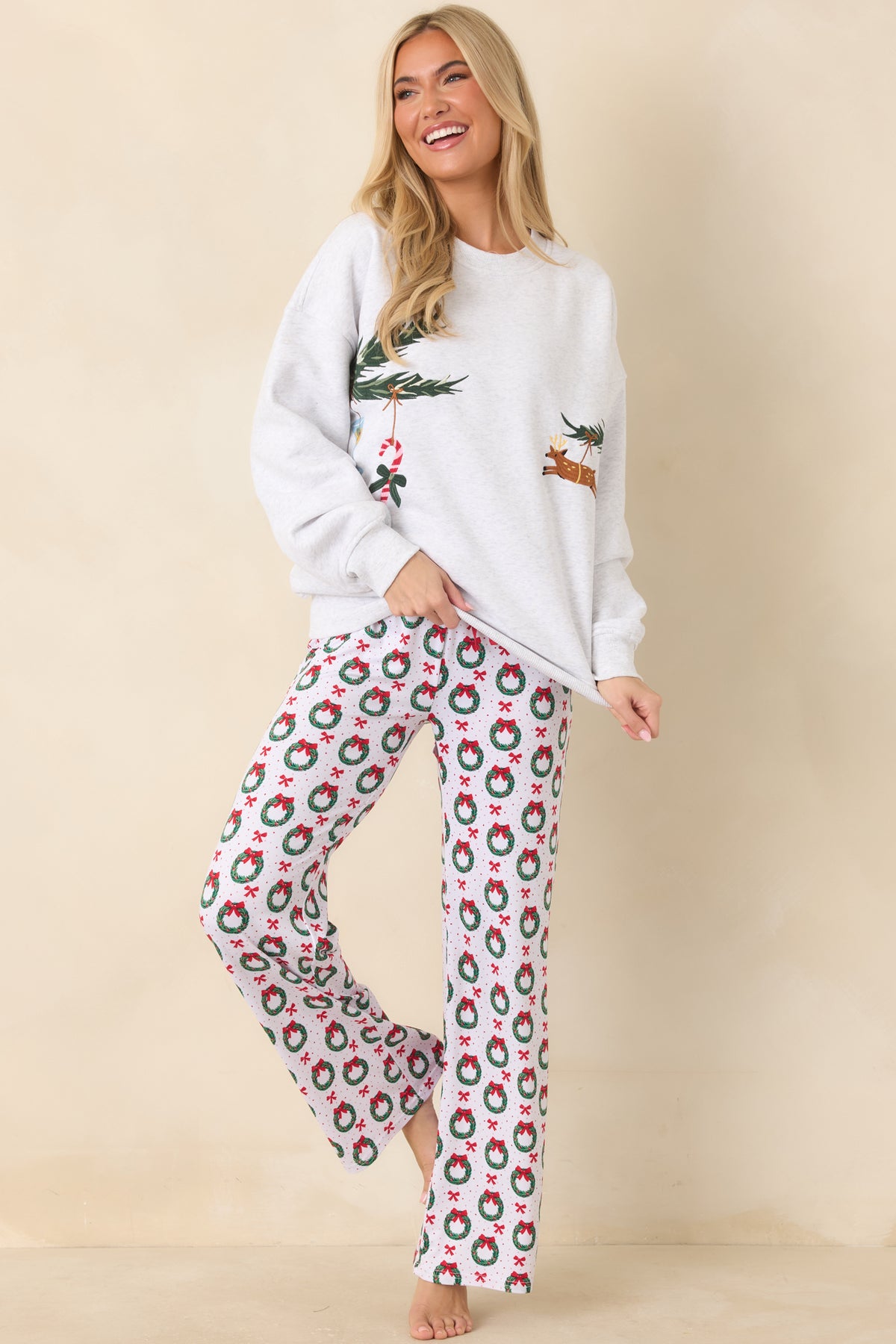Light heather grey pullover top featuring embroidered evergreen branches decorated with colorful holiday ornaments.