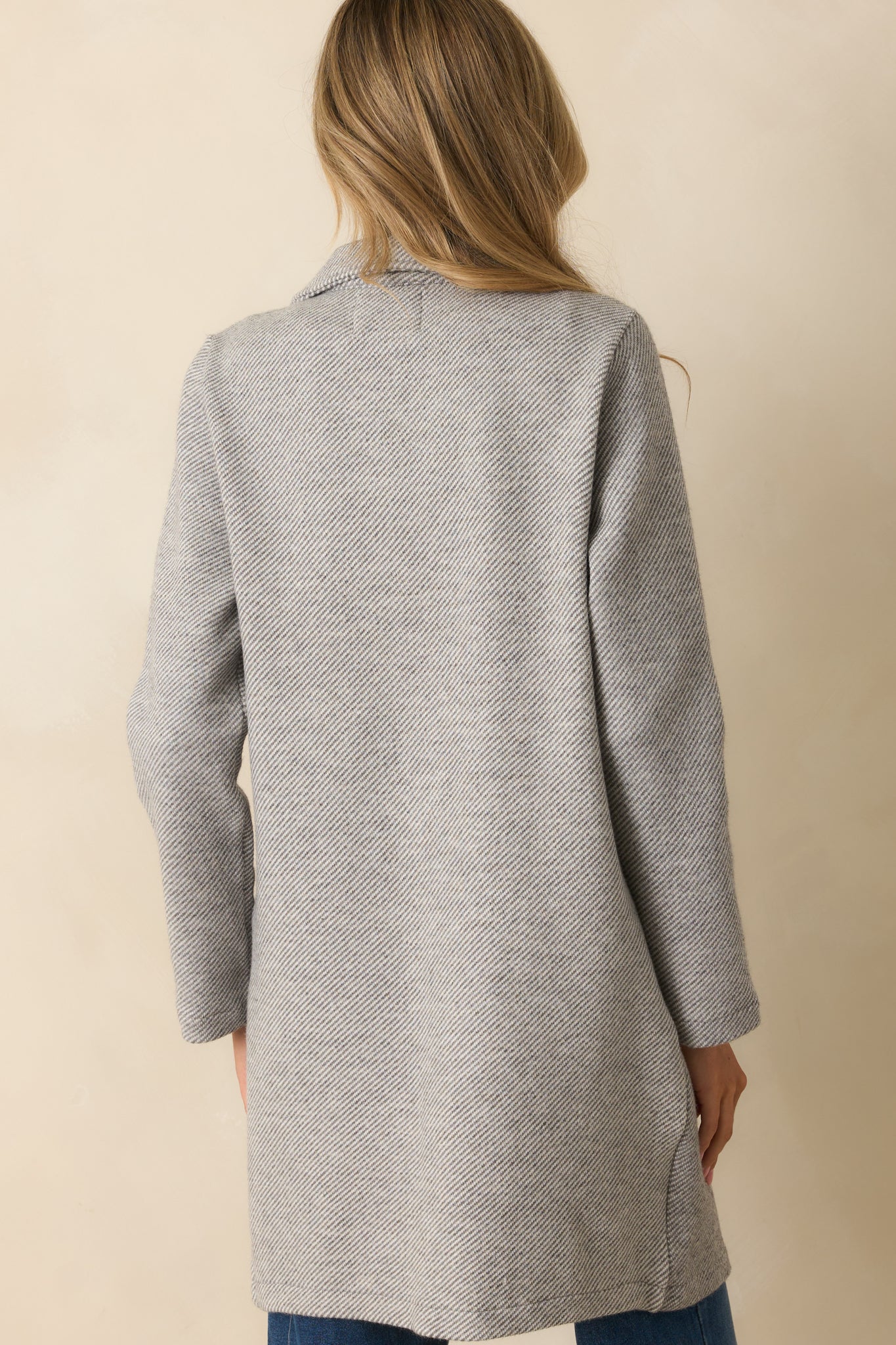 Rear view of the grey twill coat showing the straight longline silhouette and clean tailored finish.