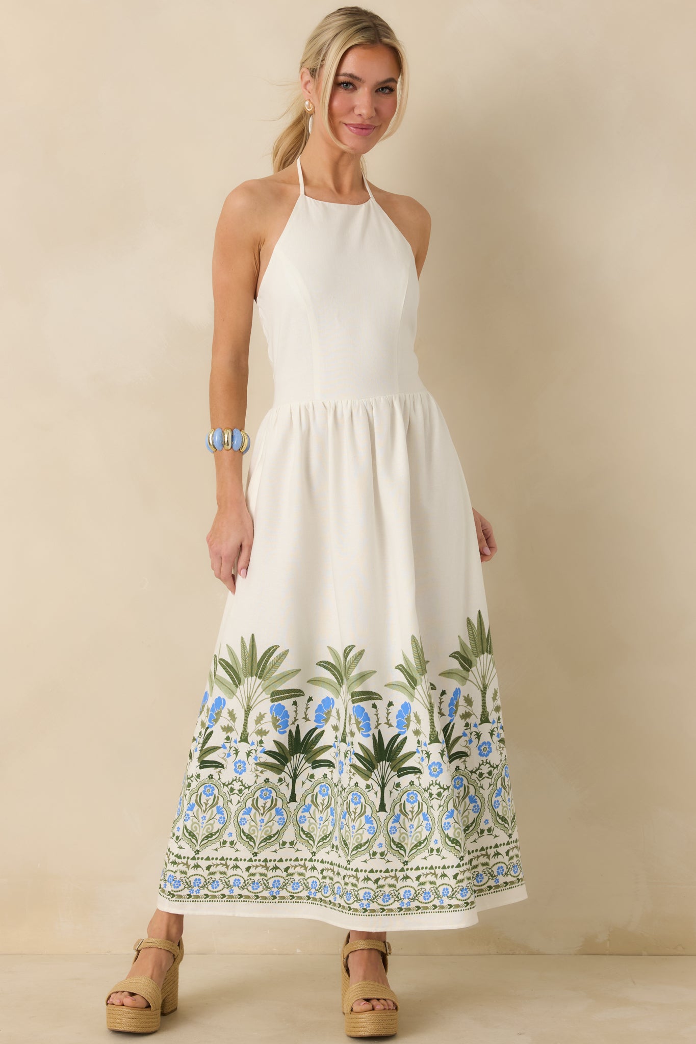Halter-neck ivory midi dress with adjustable tie-back closure and flowing skirt.