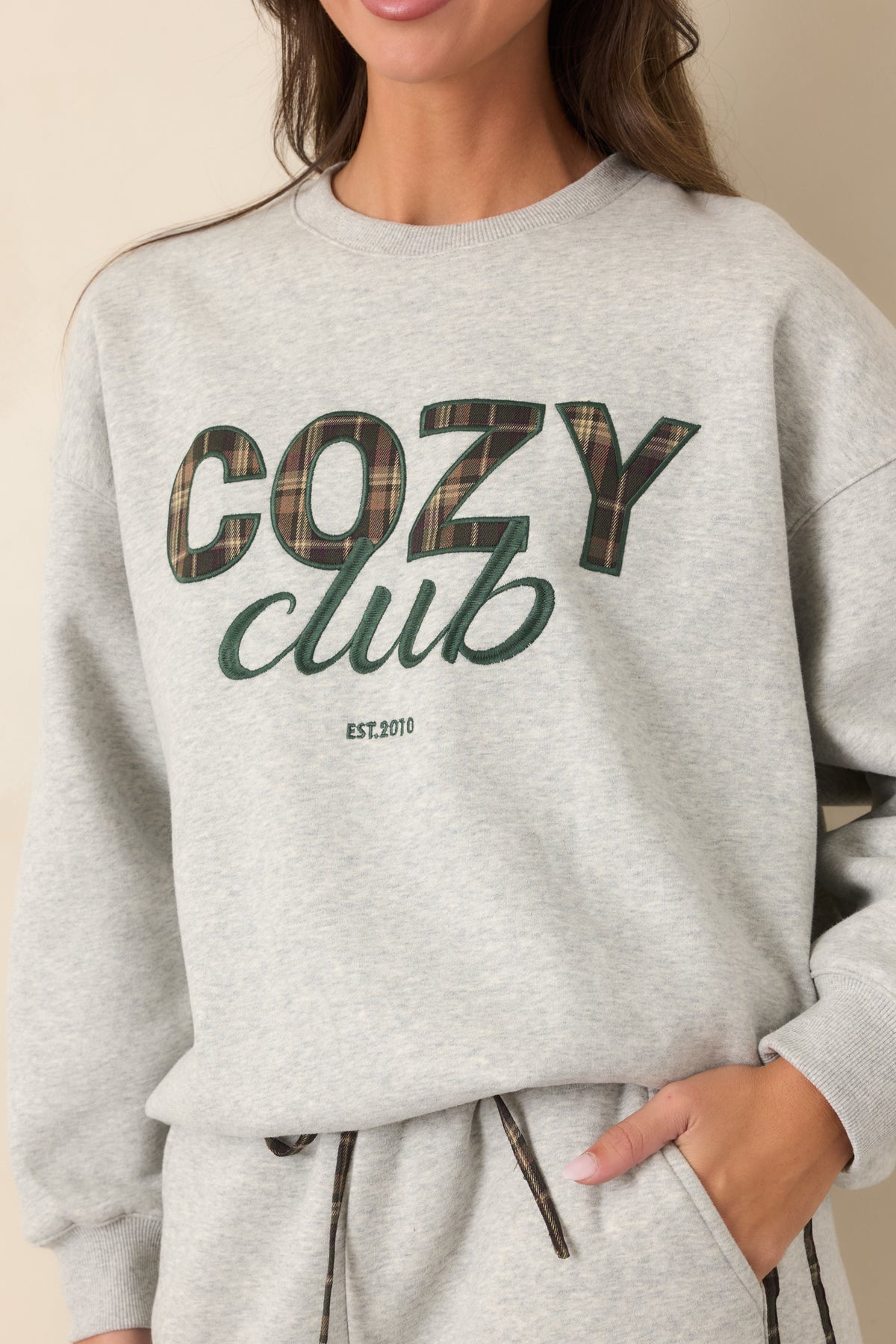 Close-up of the plaid lettering texture against the heather grey sweatshirt fabric.