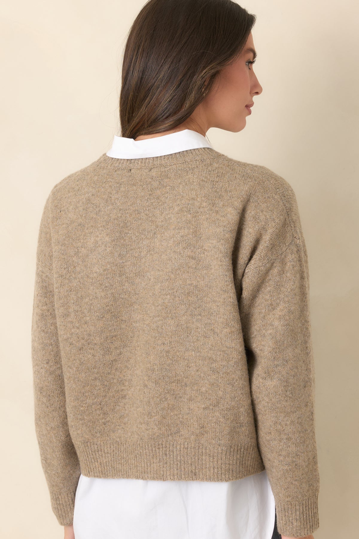 Rear of the heathered taupe sweater showcases its plain knit finish, long sleeves, and ribbed crew neckline and hem.
