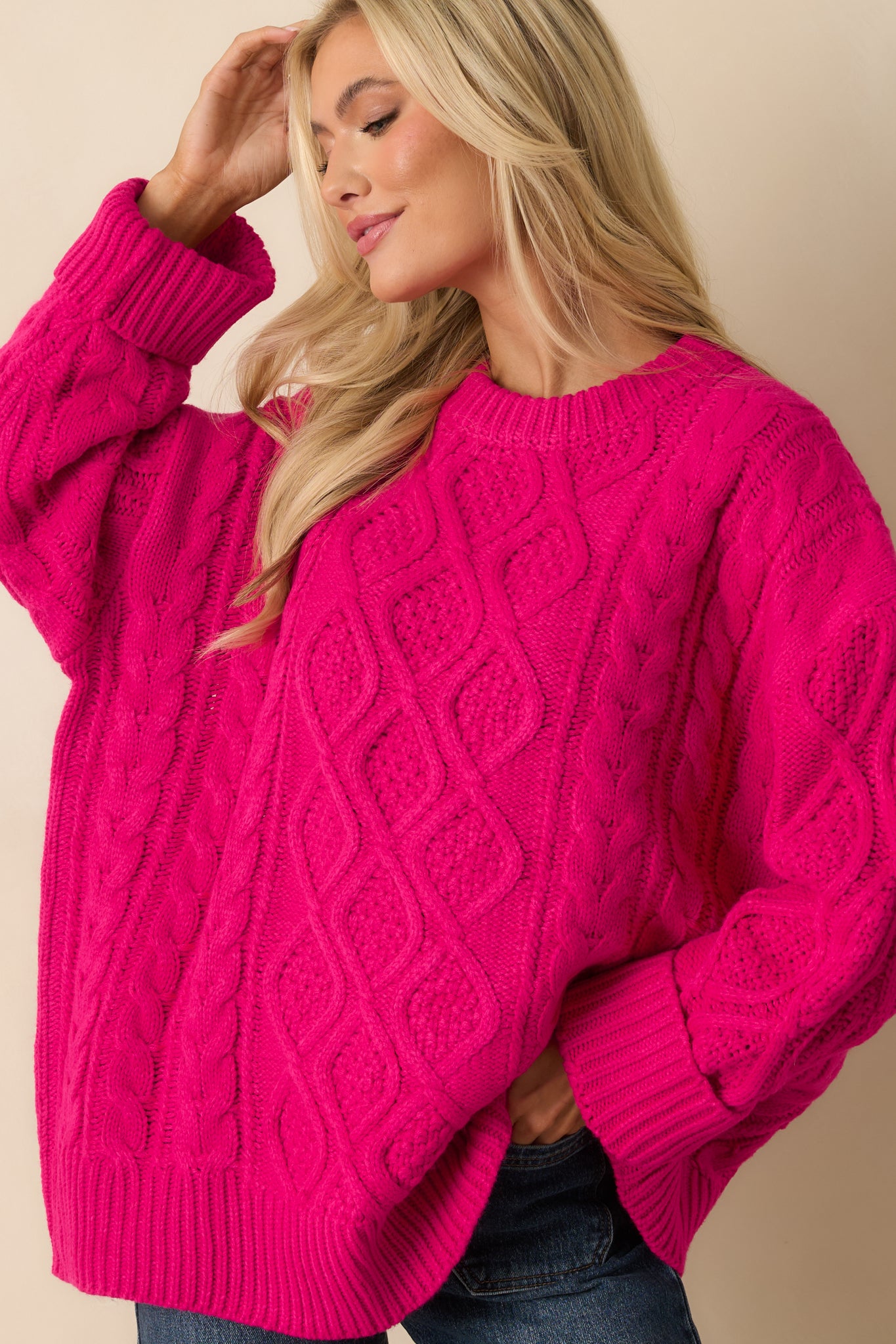 Detail of the hem and relaxed fit of the hot pink cable knit top.