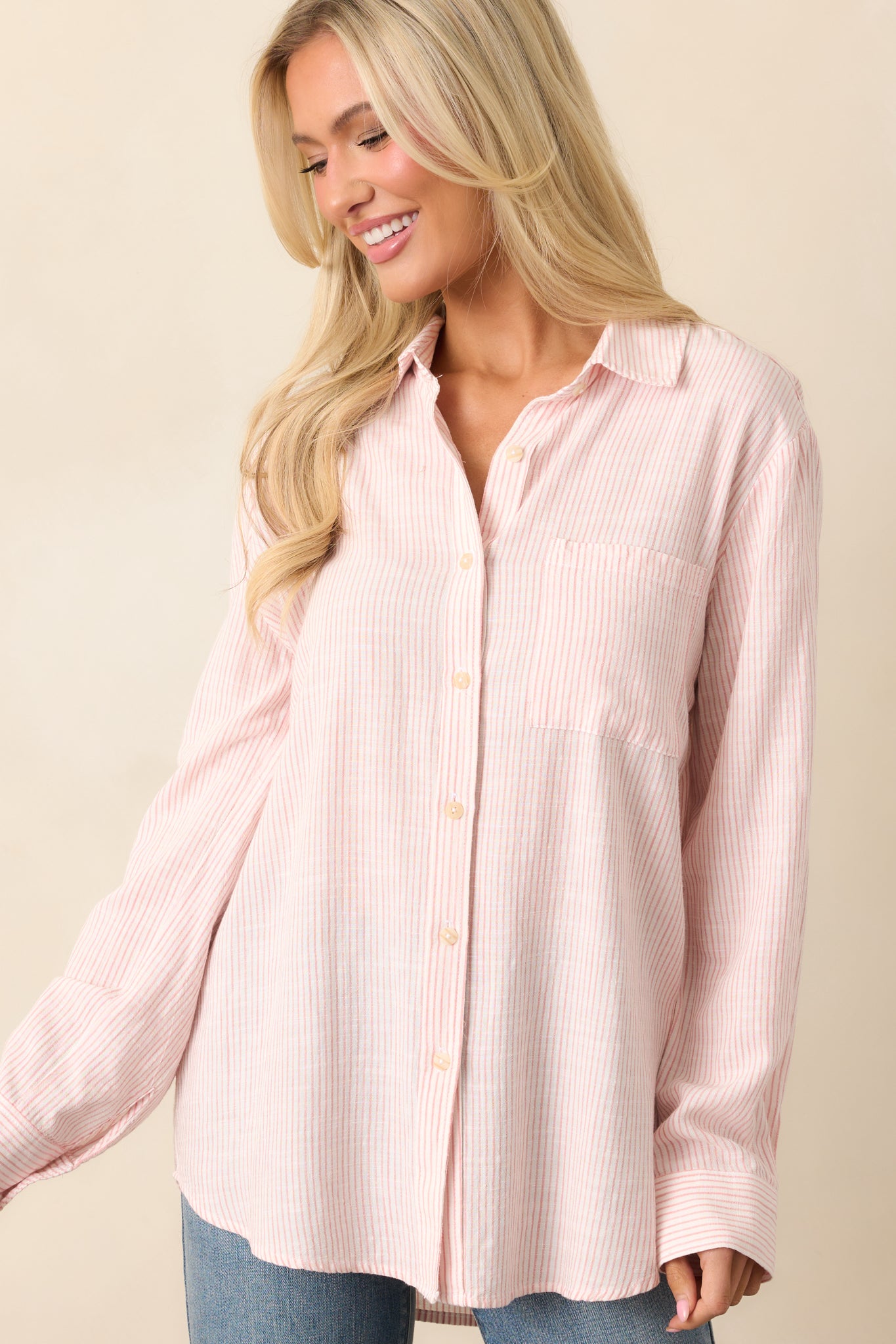 The hem of the pink striped top, emphasizing its airy linen-blend fabric and relaxed silhouette.