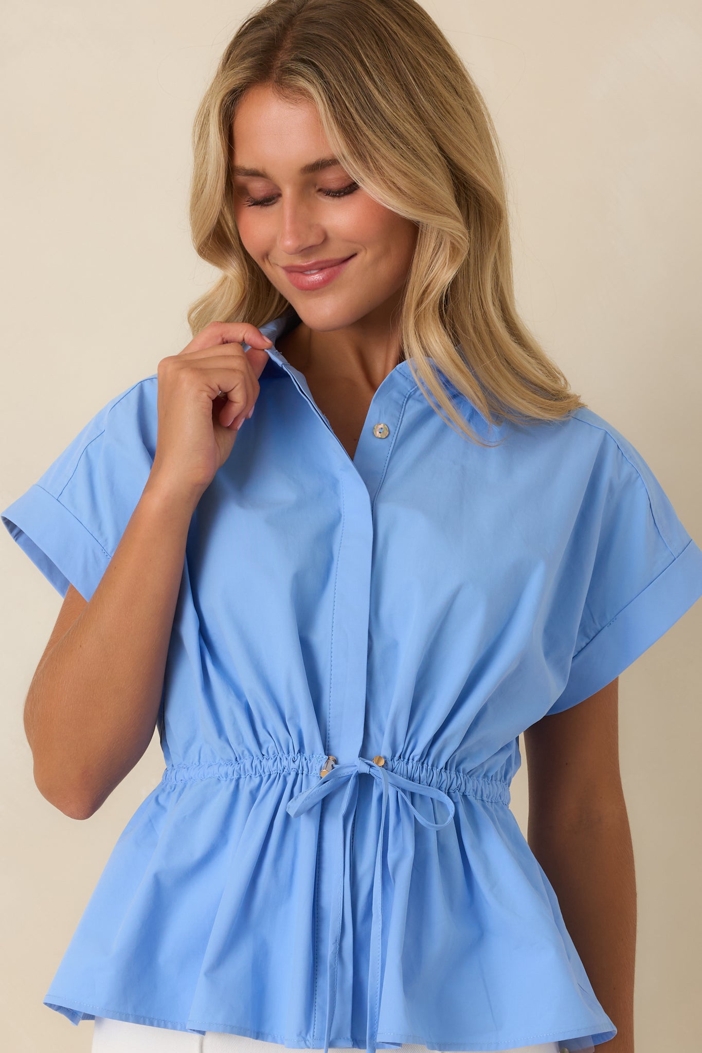 Concealed abalone shell button front creates a smooth, polished finish on this sky blue cotton button-up top.