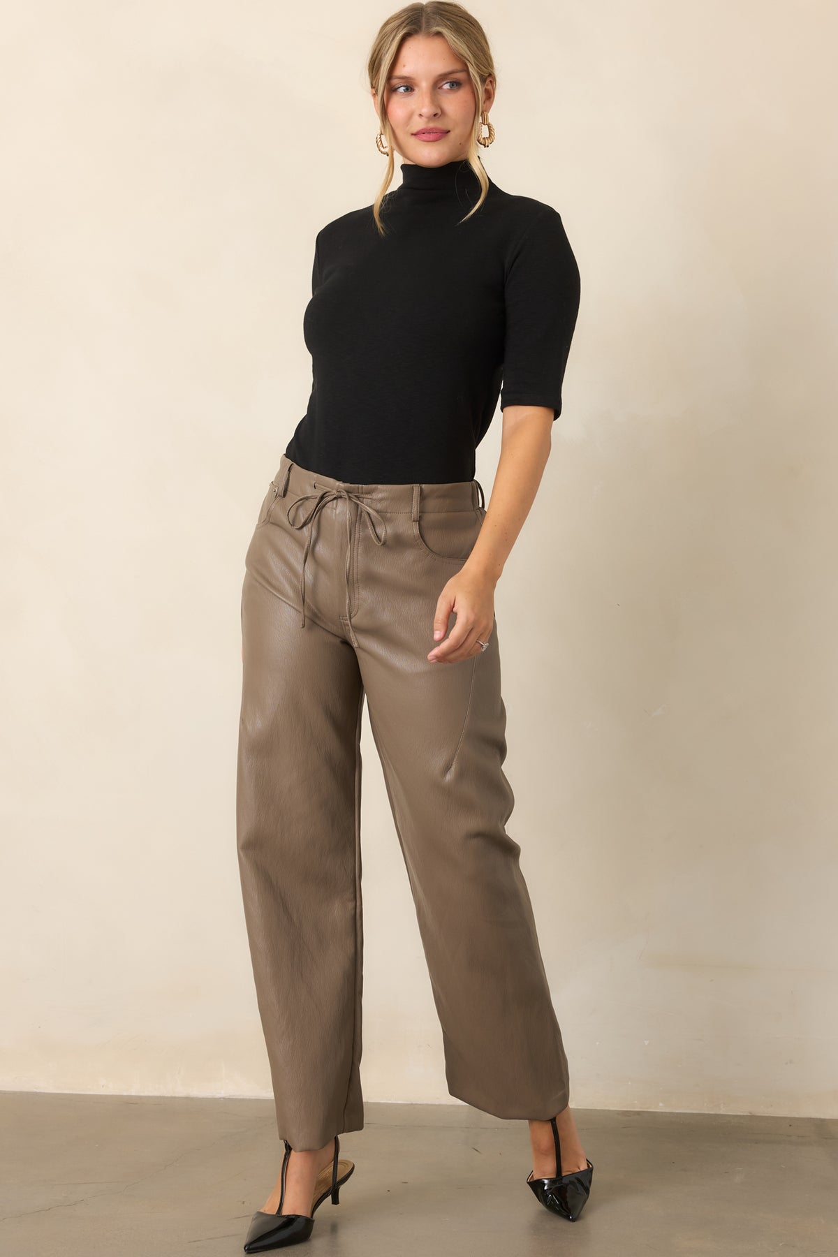 High-rise faux leather pants featuring an elastic waistband and front drawstring tie.