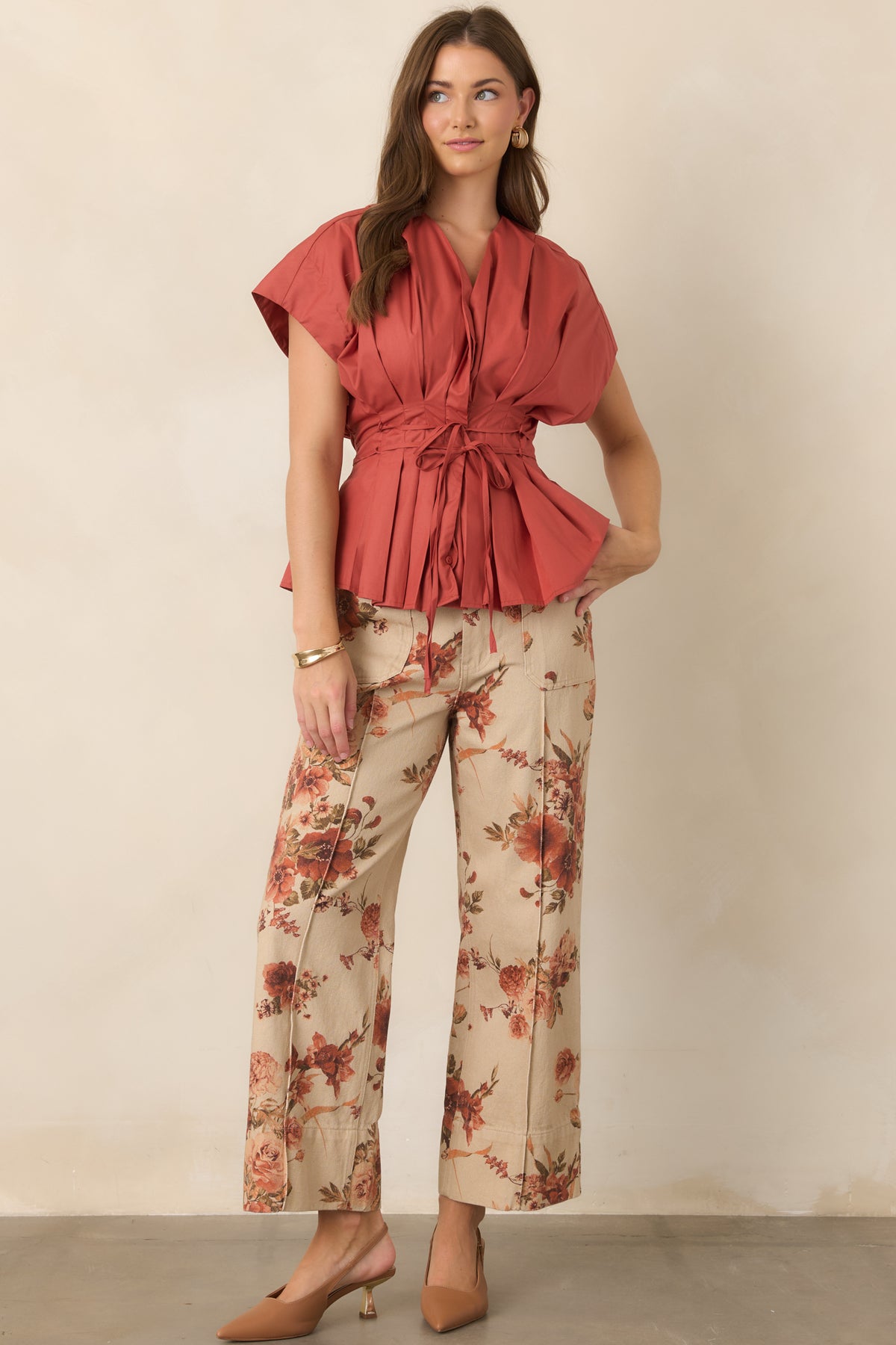 High-rise taupe pants showcasing a botanical rust floral pattern, structured shape, and cropped wide-leg fit with patch pockets.