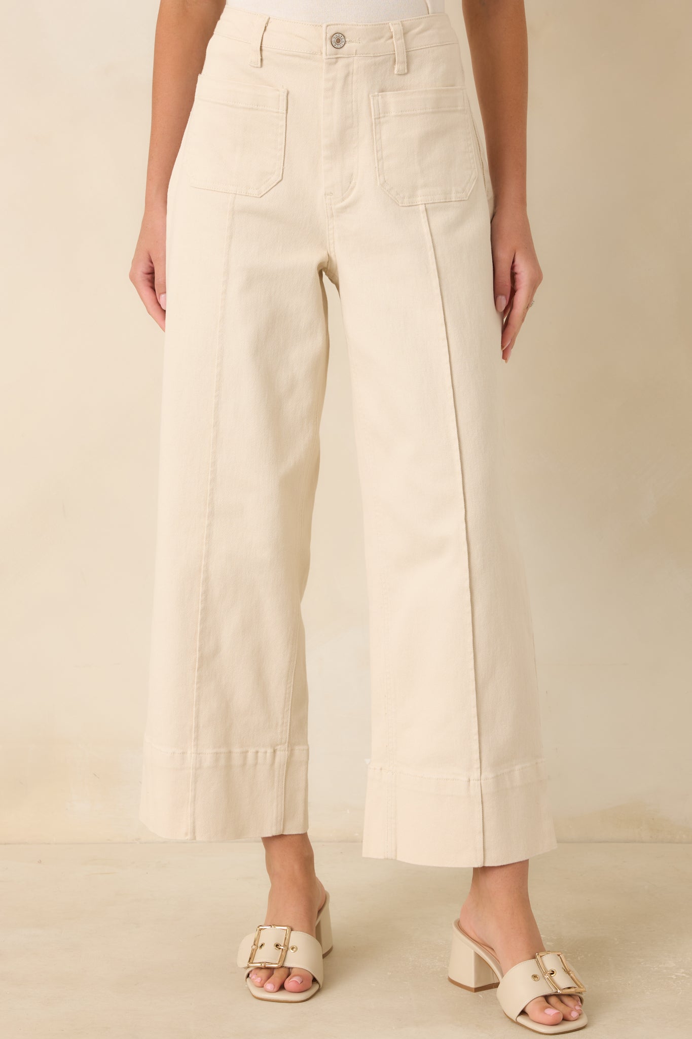 Close view of the high-rise waistband and oversized front patch pockets on the ivory utility-inspired pants.