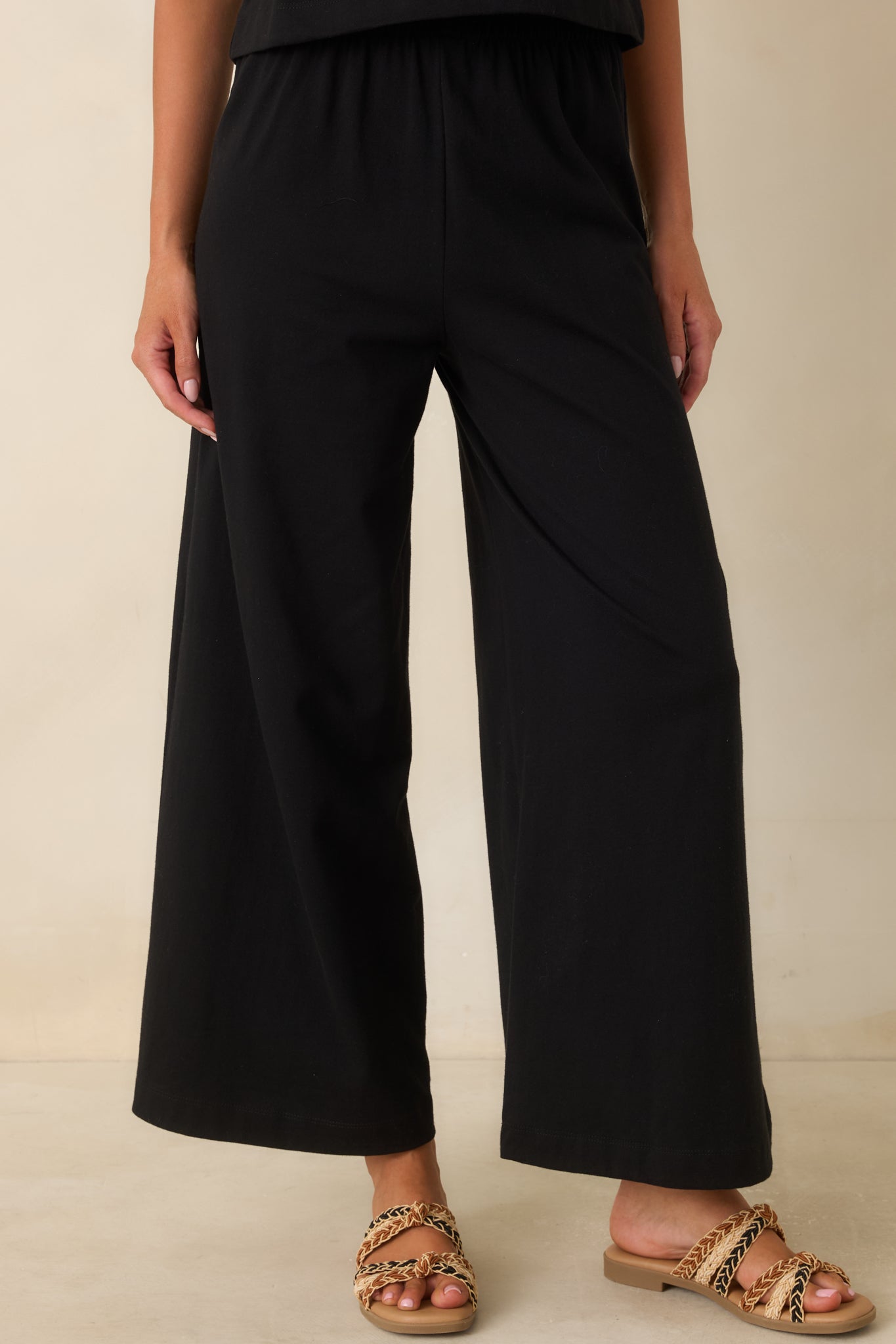 Detailed view of the high waisted elastic waistband on soft black jersey pants.