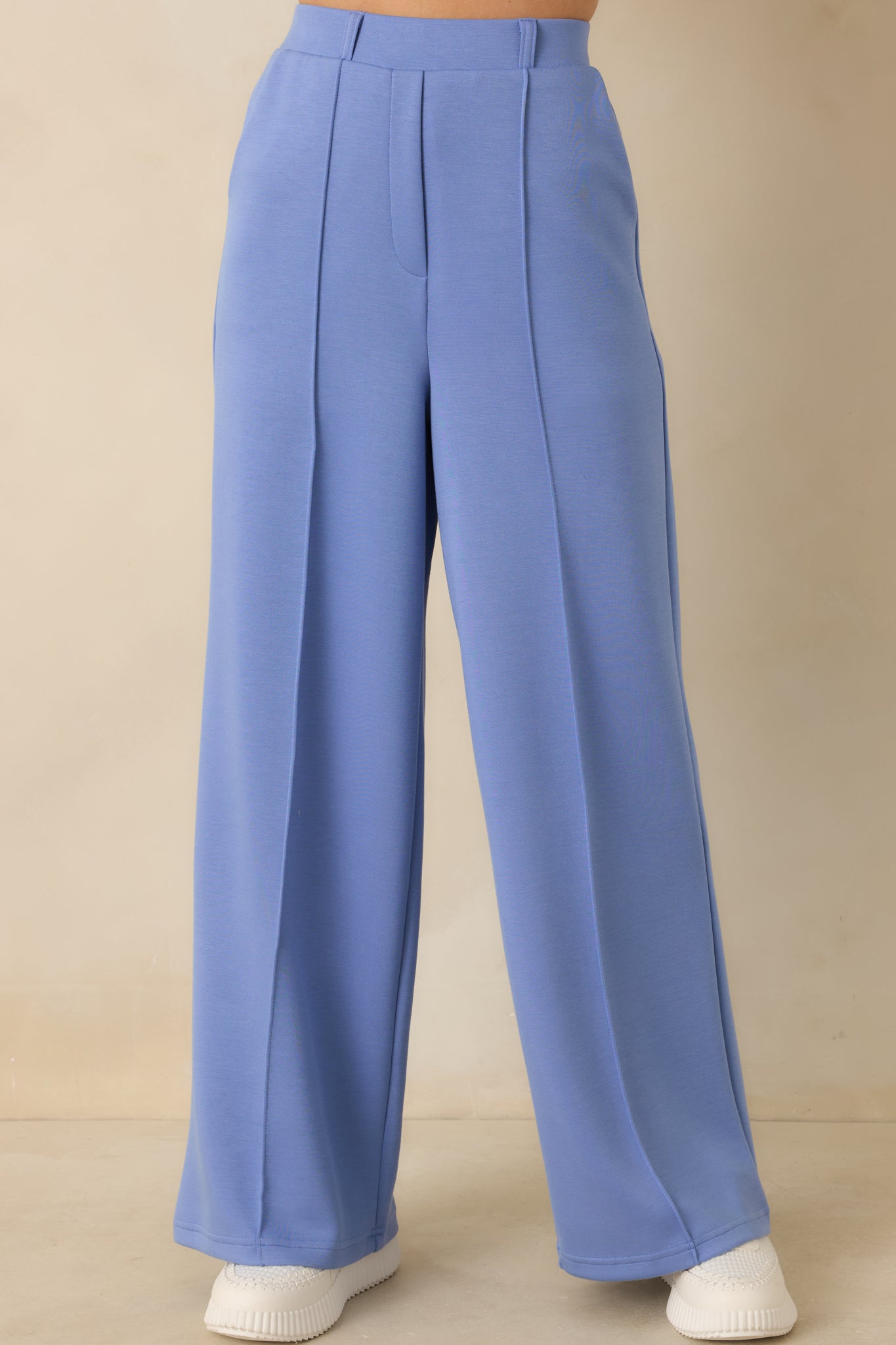 High-waisted blue pants highlighting the structured waistband with belt loops and neatly placed front pleats.