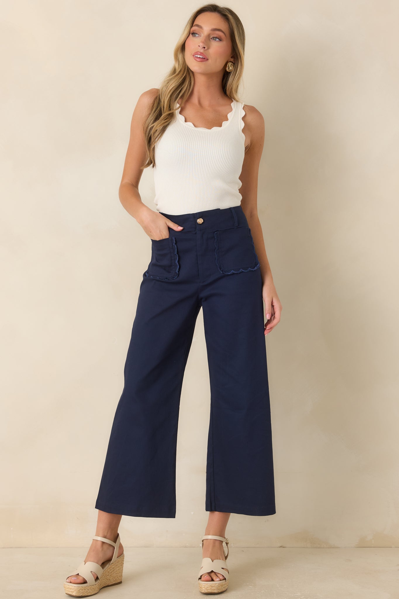 High-waisted cropped pants featuring a structured cotton blend fabric, wide-leg silhouette, scalloped front pockets, and a polished gold-tone button closure.