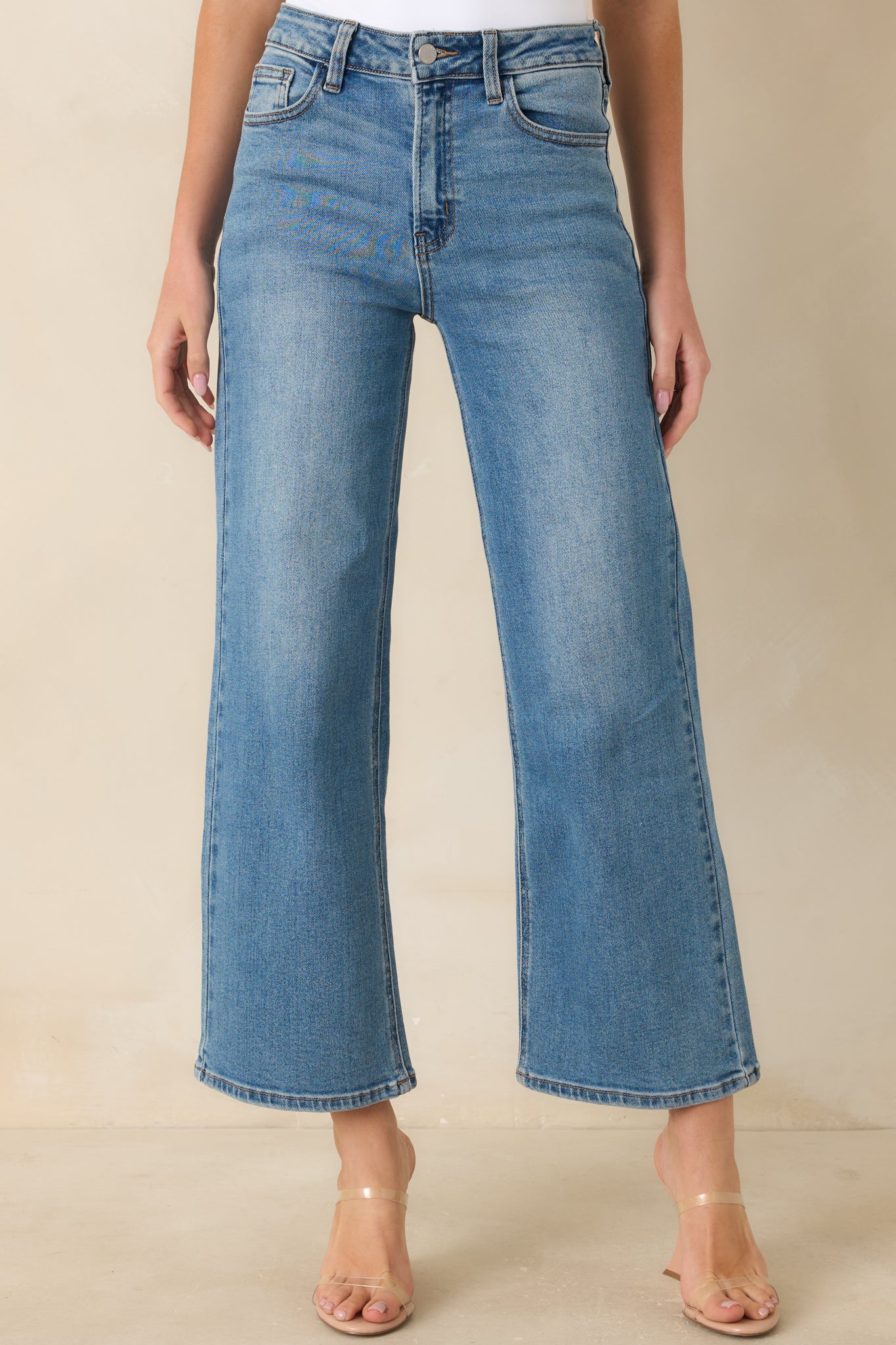 High-waisted jeans highlighting the button and zipper closure with sturdy belt loops at the waistband.