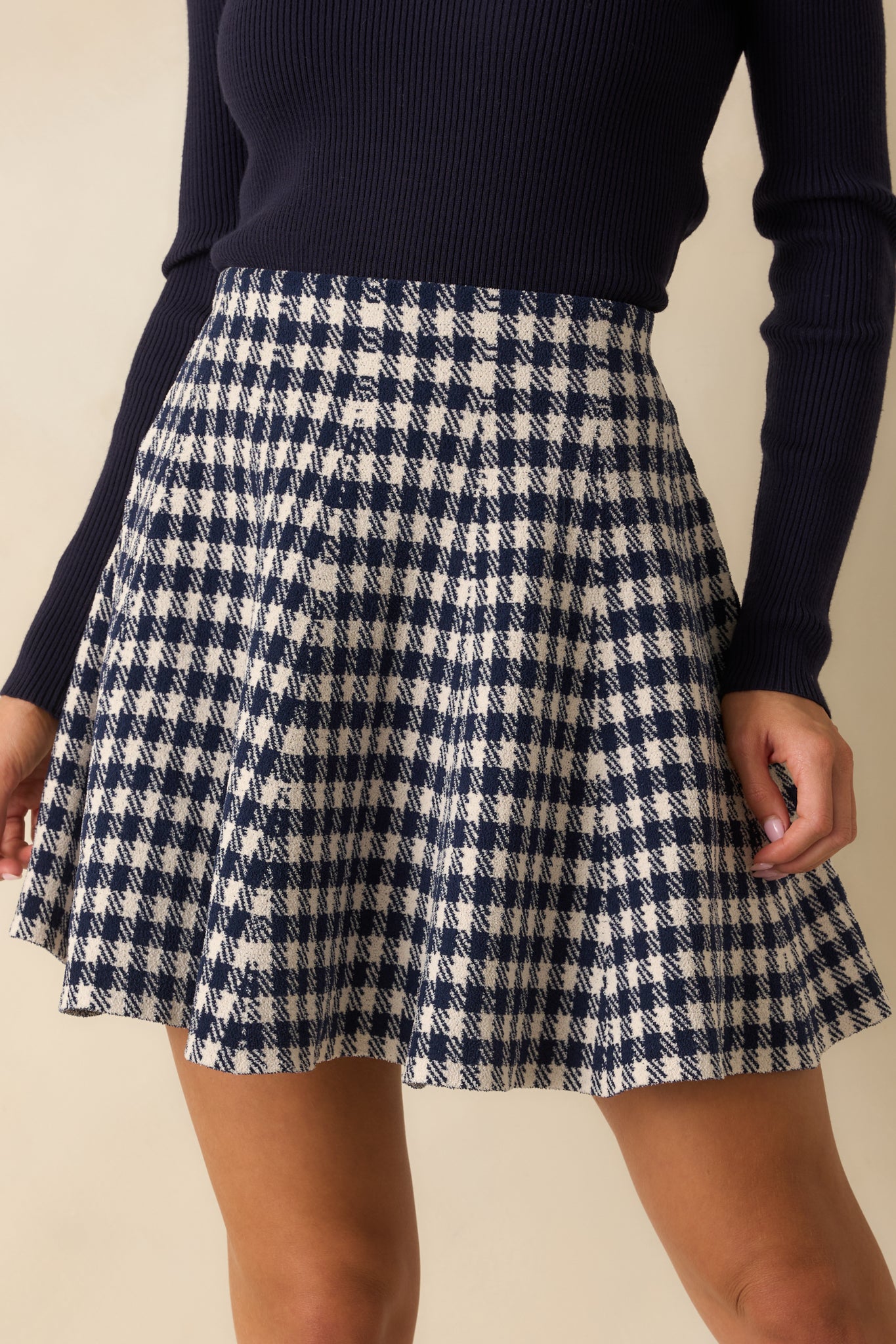 Navy blue gingham knit mini skirt with a high-waisted fit and flared silhouette.