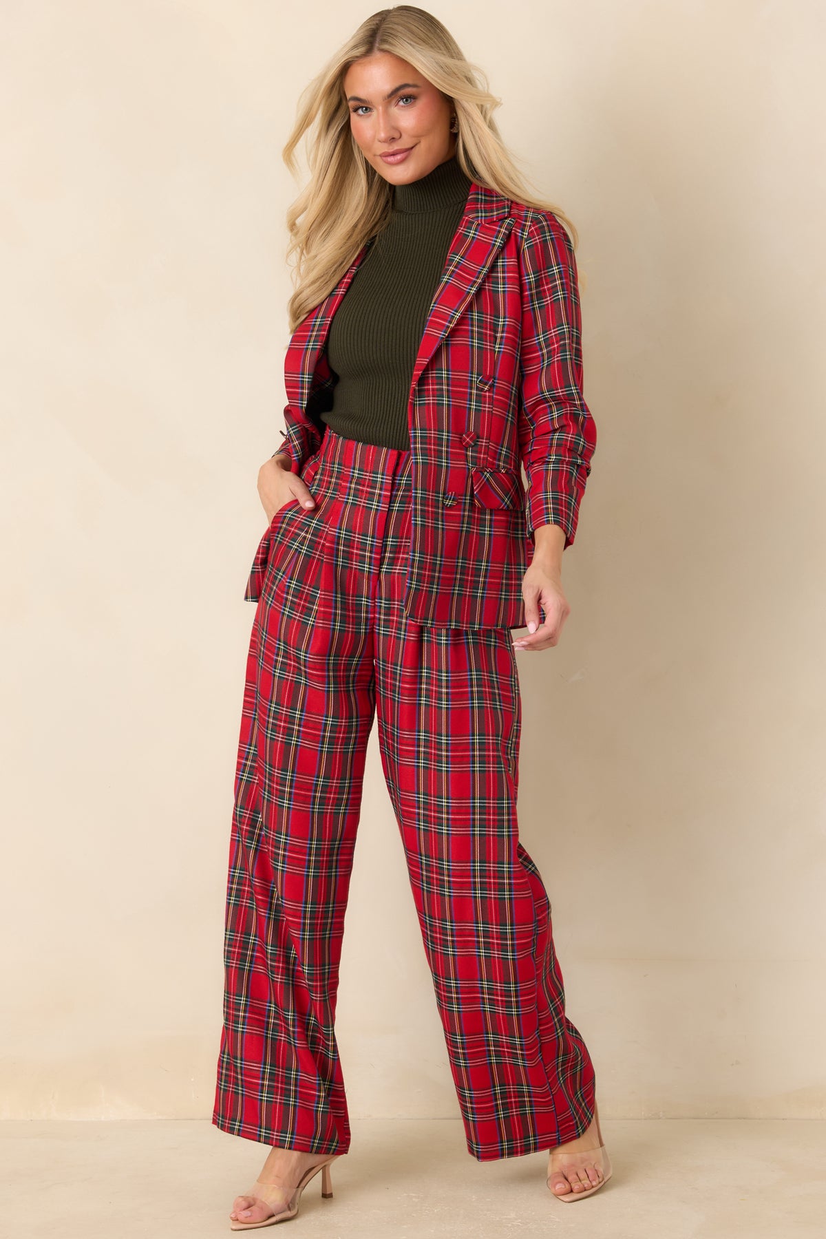 High-waisted red plaid trousers with structured front pleats and a flowing full-length cut.
