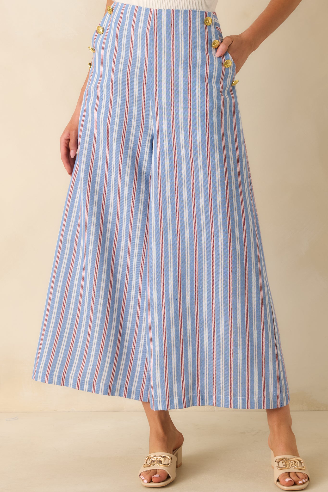 High-waisted striped pants with decorative gold-tone hip buttons, cropped length, and a structured yet relaxed fit.
