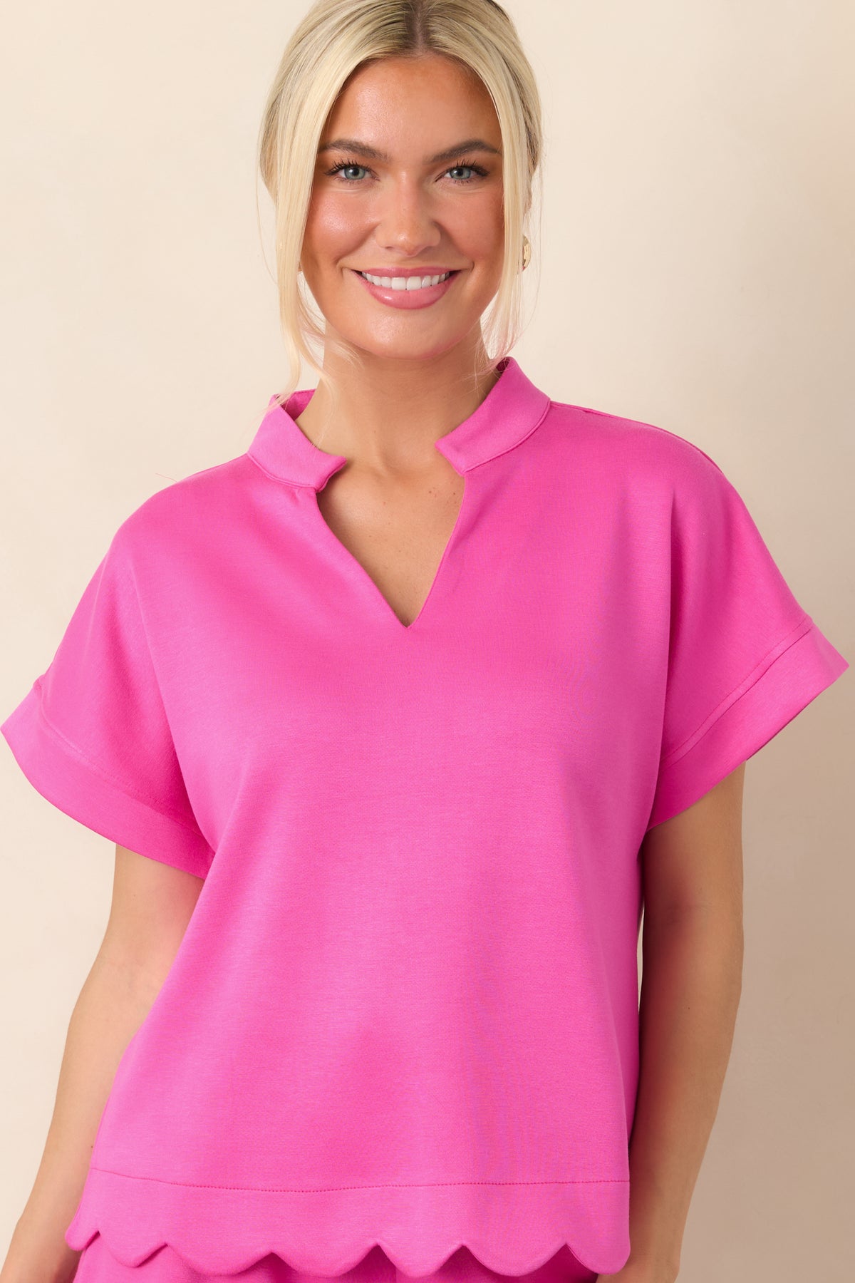 Detailed view of the short cuffed sleeve and relaxed pink silhouette, showcasing the top’s polished structured fabric.