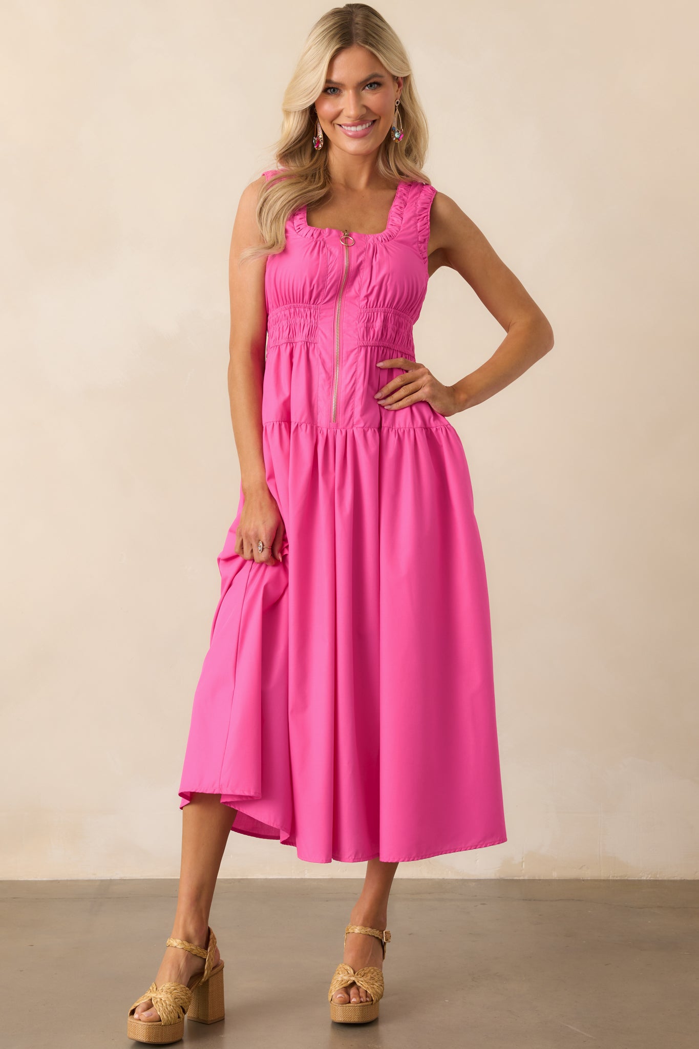 Front view of a hot pink midi dress with a scoop neckline, sleeveless cut, and o-ring zip front closure.