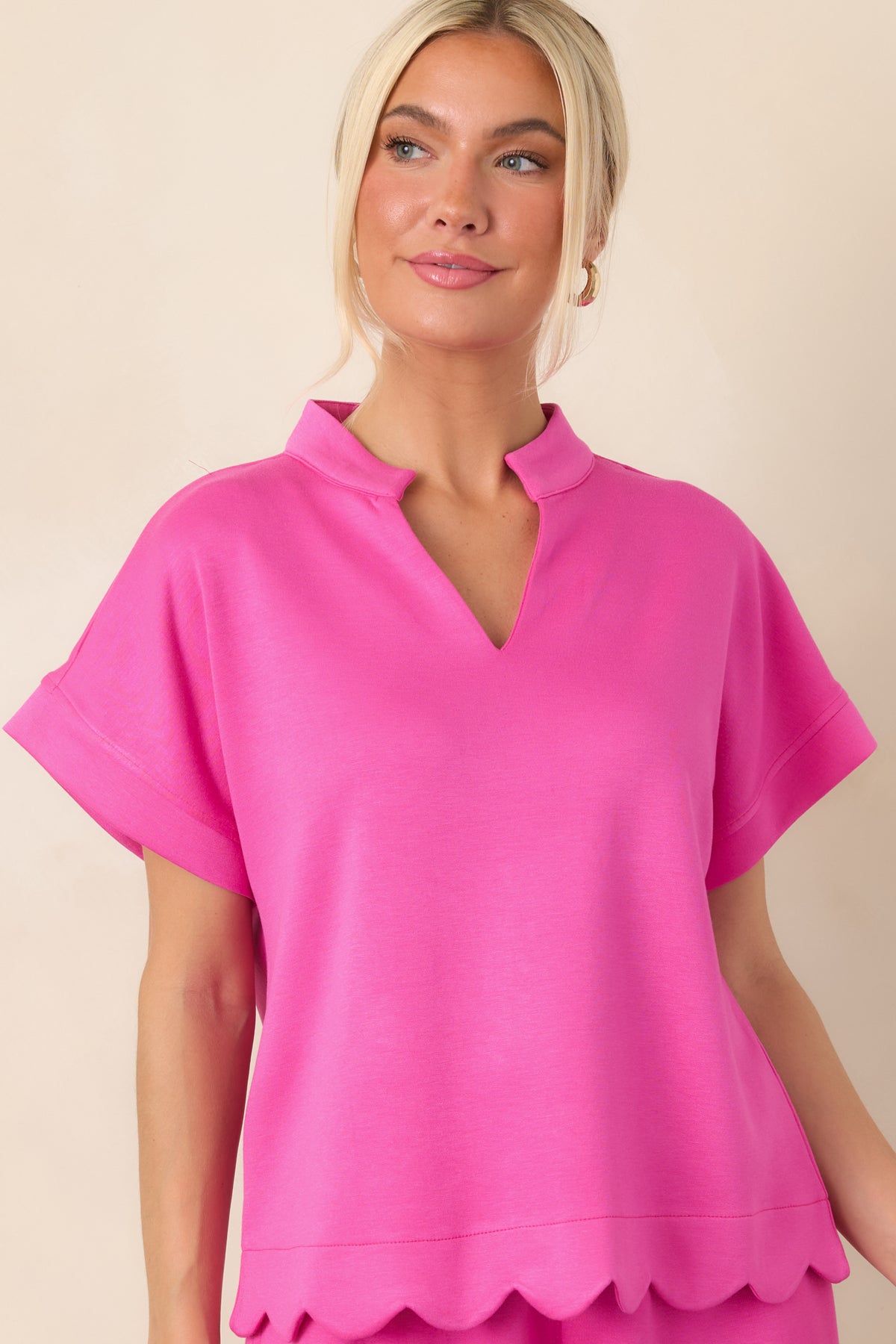 Close view of the hot pink top’s scalloped hemline, emphasizing the softly curved edging and relaxed shape.