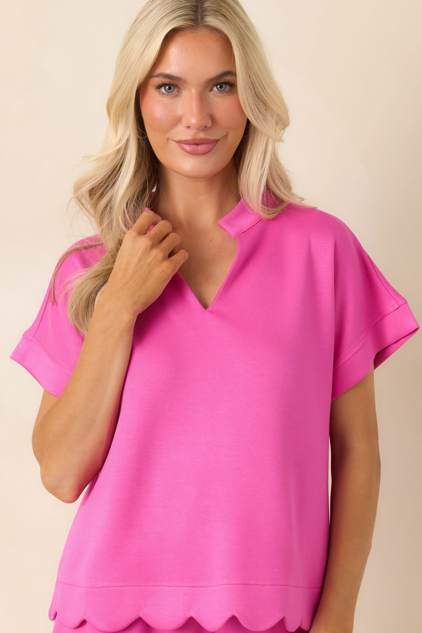 Close view of the hot pink top highlighting the split neckline, standing collar, and soft structured fabric.