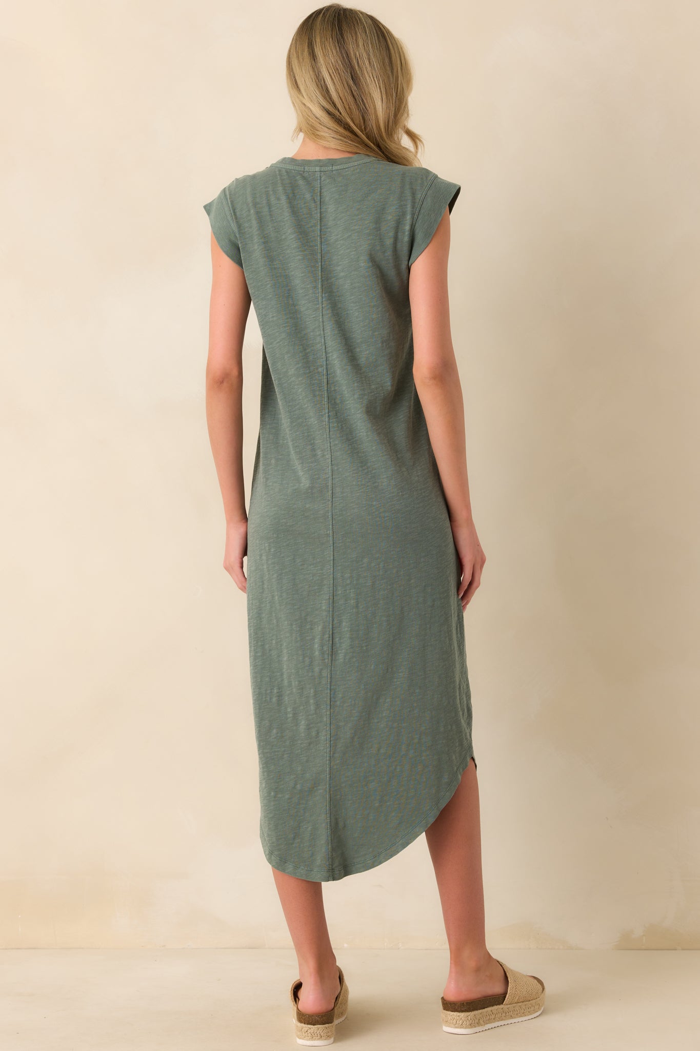 A view from behind of the hunter green midi dress displaying the back center seam detail and the gentle curve of the scoop hem