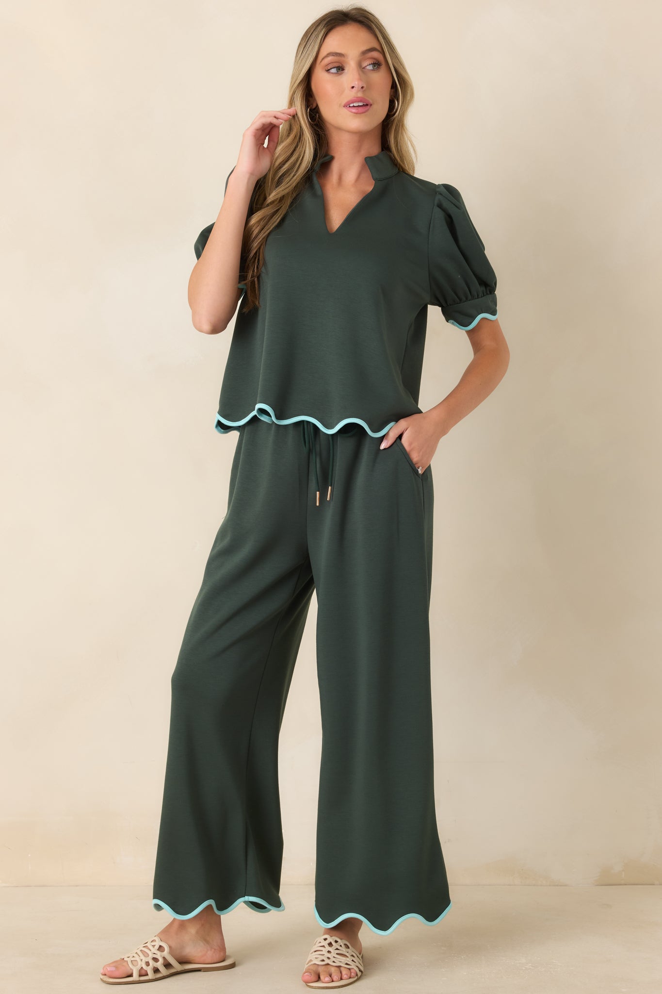 Hunter green knit pants featuring a relaxed wide leg silhouette, drawstring waistband, and scalloped hem trim.