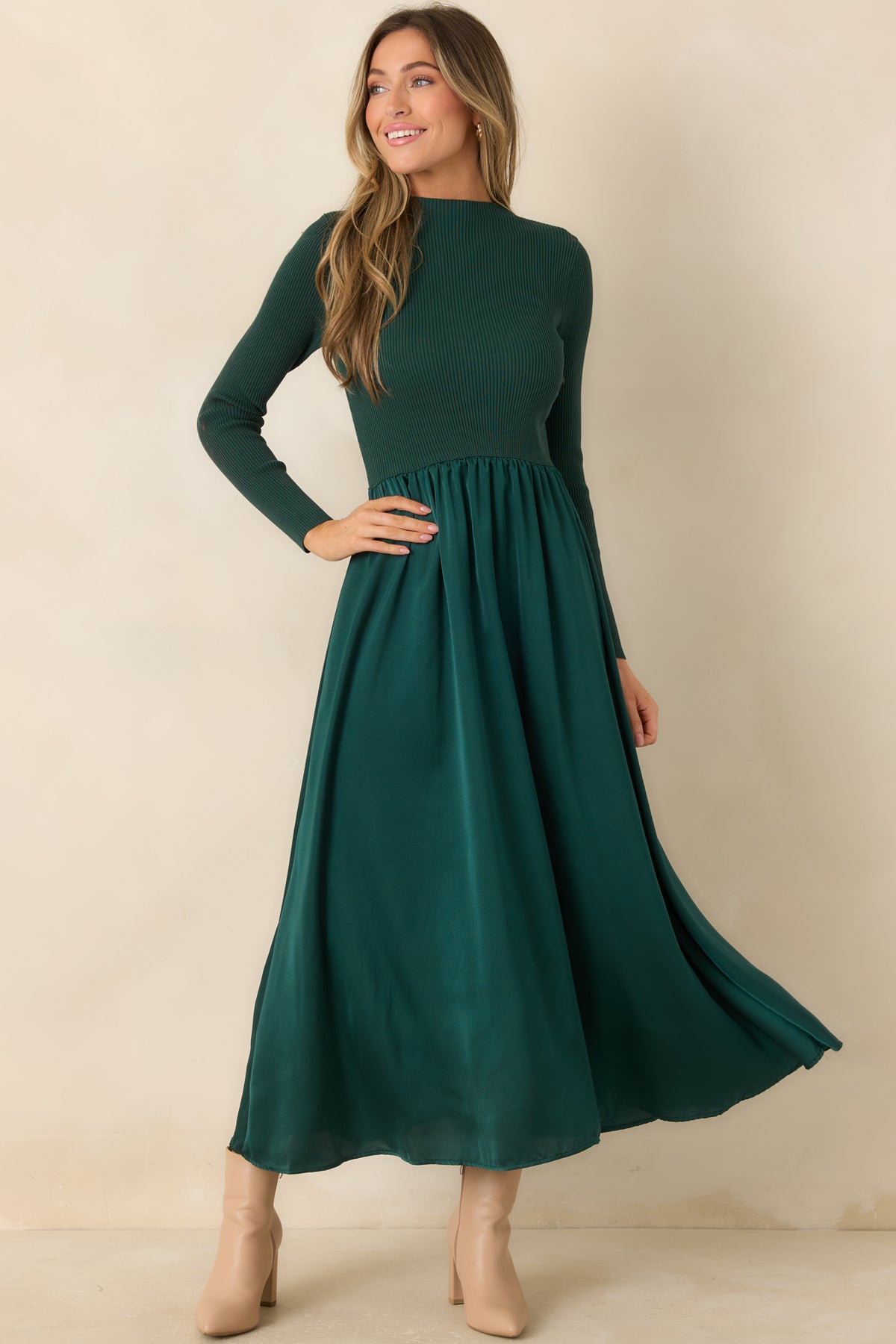 Seasonal hunter green dress with a sleek mock neckline, fitted sleeves, and a softly draped skirt.