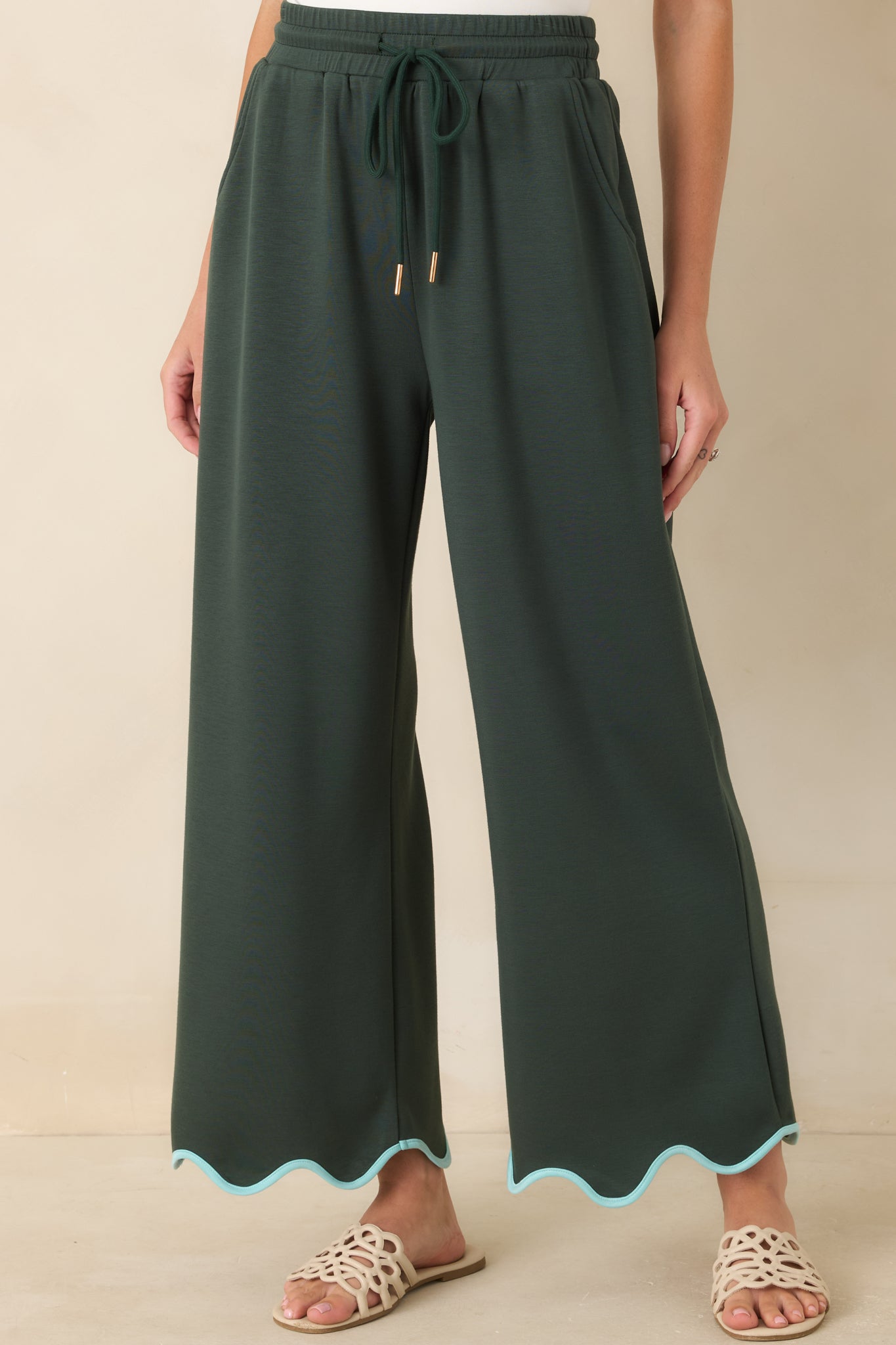 The front of these hunter green pants highlights the drawstring waistband and wide leg shape.