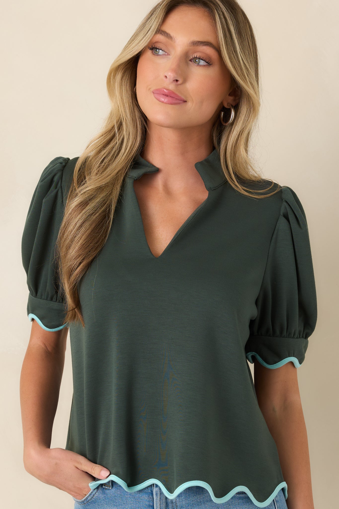 Light blue edging creates contrast along the sleeves and hem of this hunter green top.