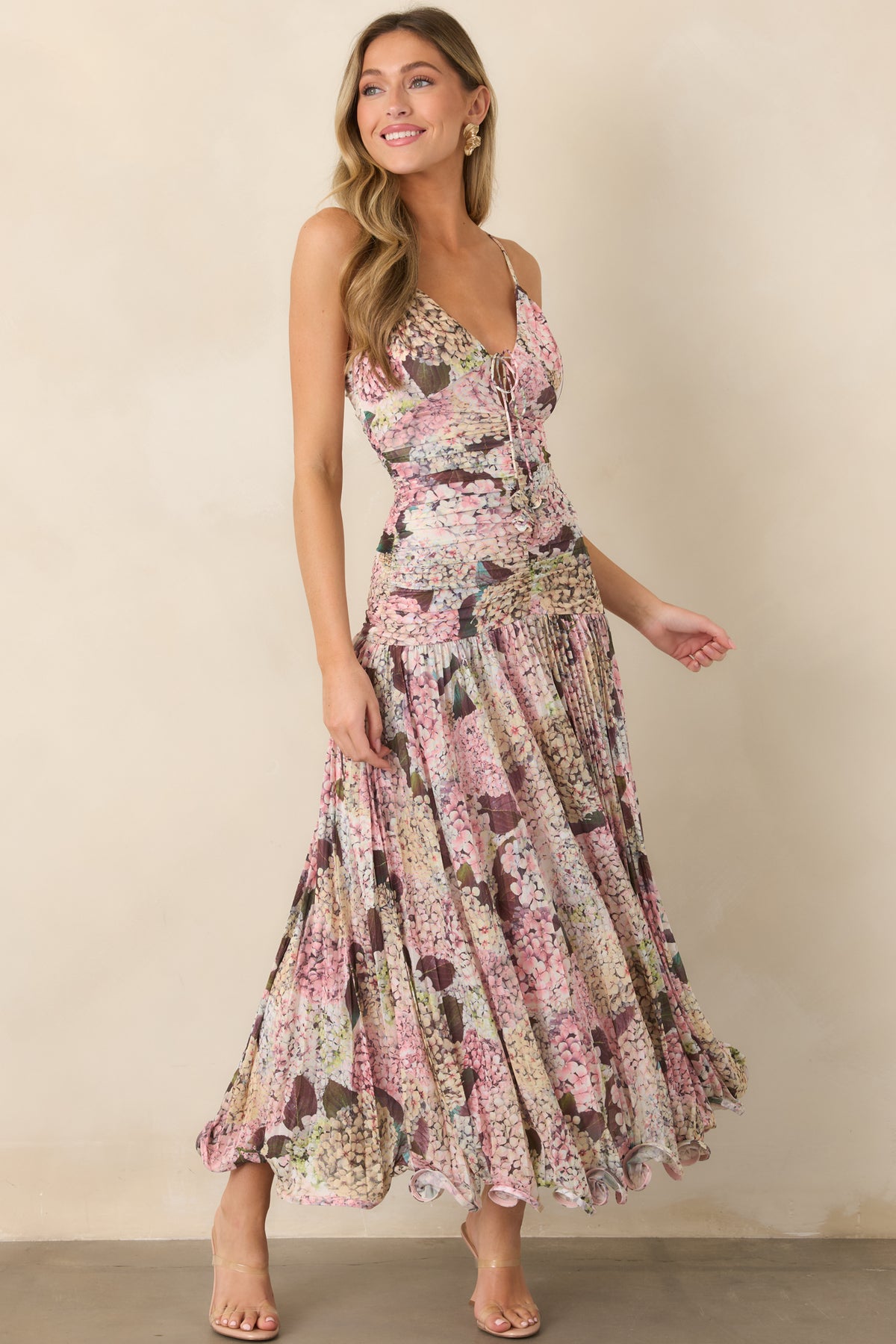Hydrangea-inspired floral maxi dress with adjustable spaghetti straps, a tied V-neckline, sculpted ruched bodice, flowing gathered skirt, and feminine wavy hem.